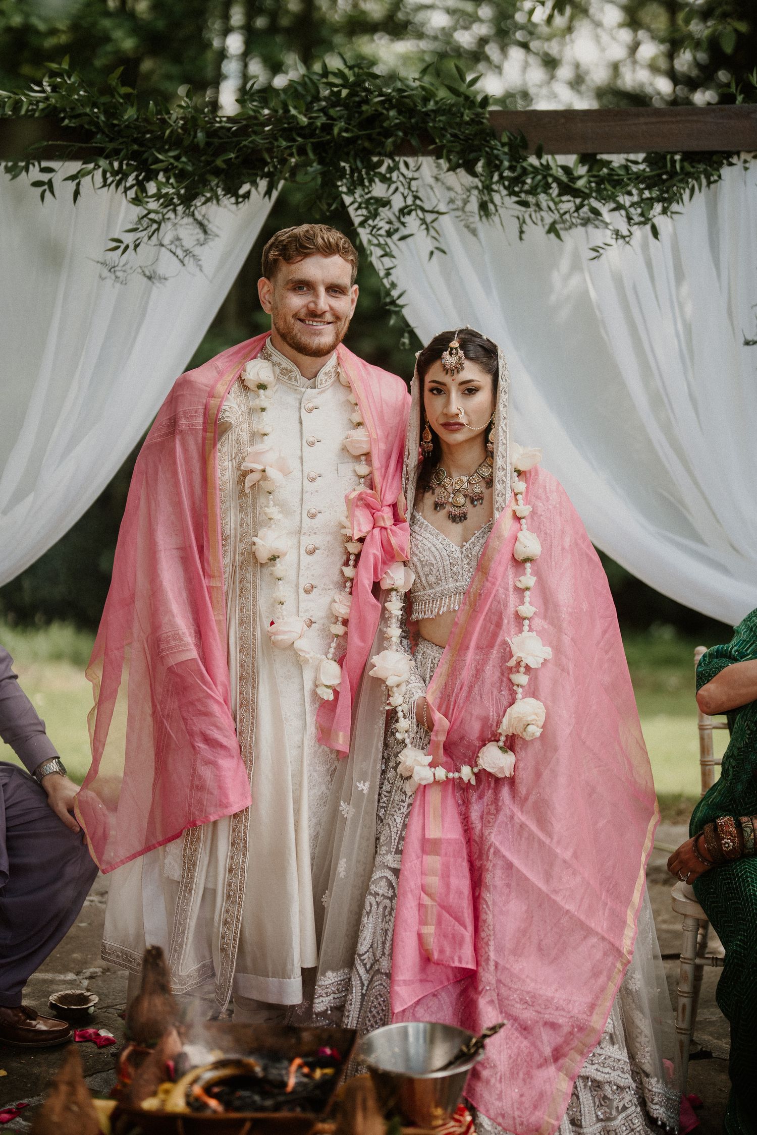 Traditional wedding attire featuring intricate white and pink embroidered garments during ceremony.