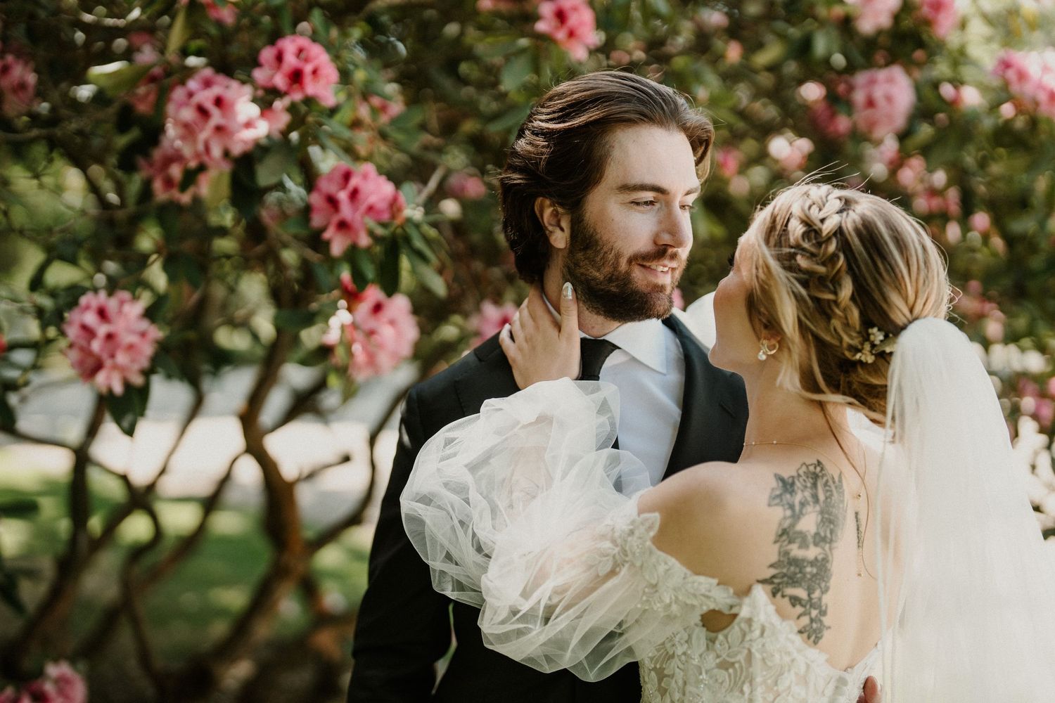 Romantic portrait among blooming pink flowers in garden setting.