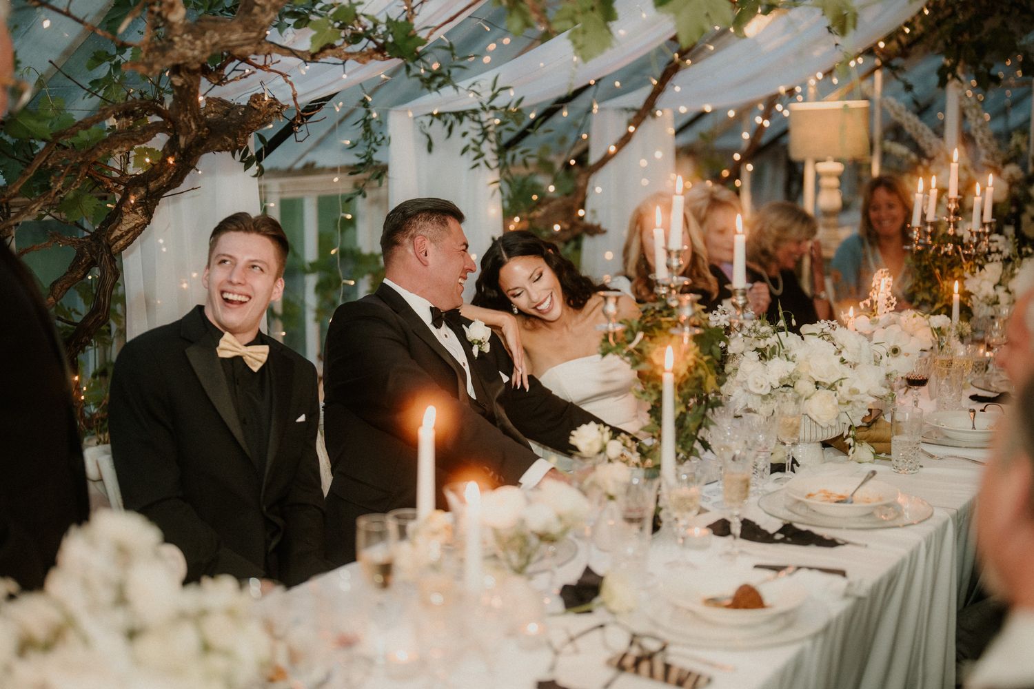 Elegant wedding reception table decorated with candlelight, greenery, and place settings for an intimate dinner.