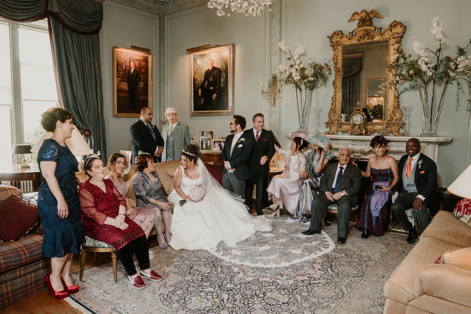 Wedding guests gathered in formal sitting room for group photographs.