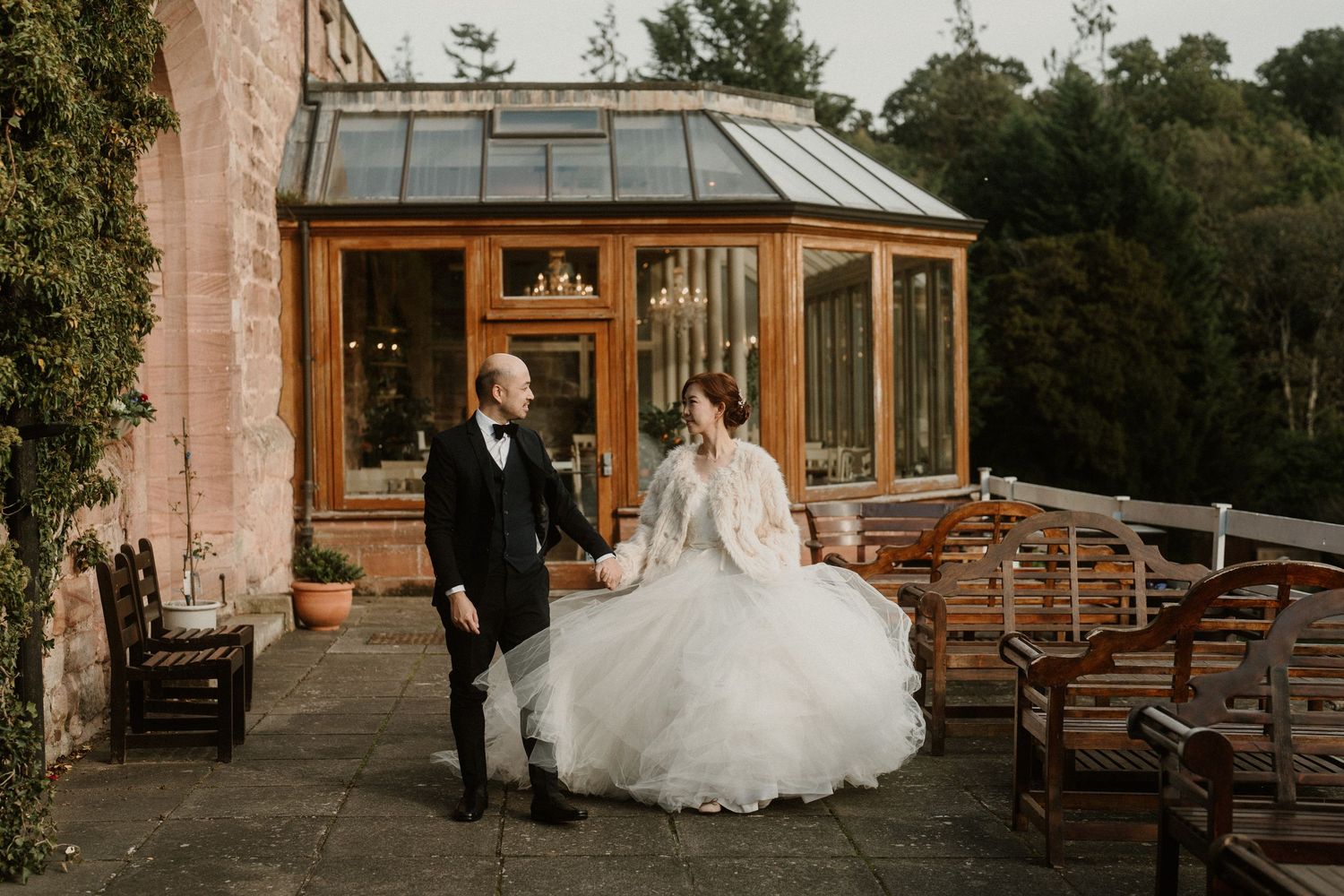 Outdoor wedding venue with rustic stone building and wooden benches.