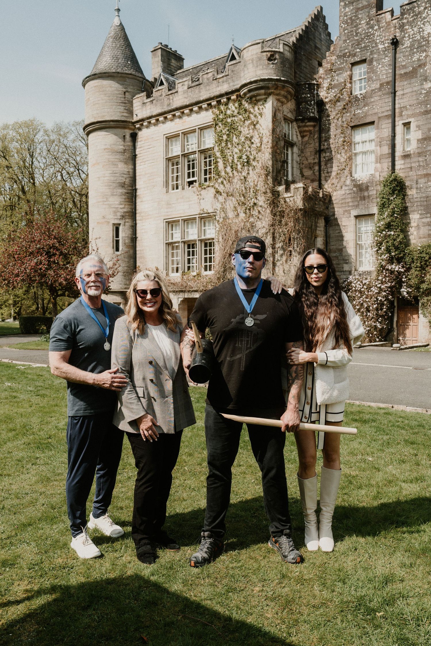 Wedding party posing for photos in front of a historic stone castle.