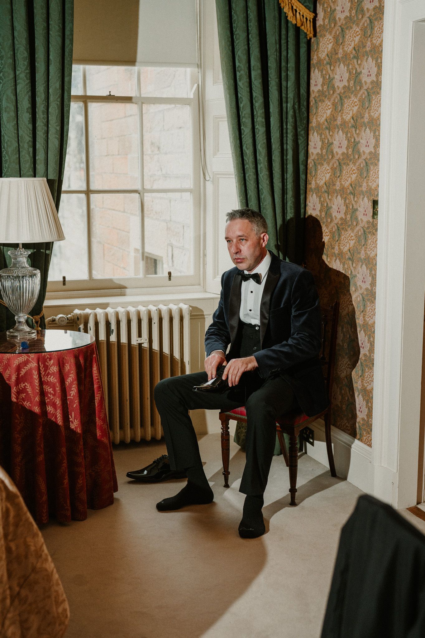 A formal event space with green curtains and traditional decor featuring a person seated in contemplation.