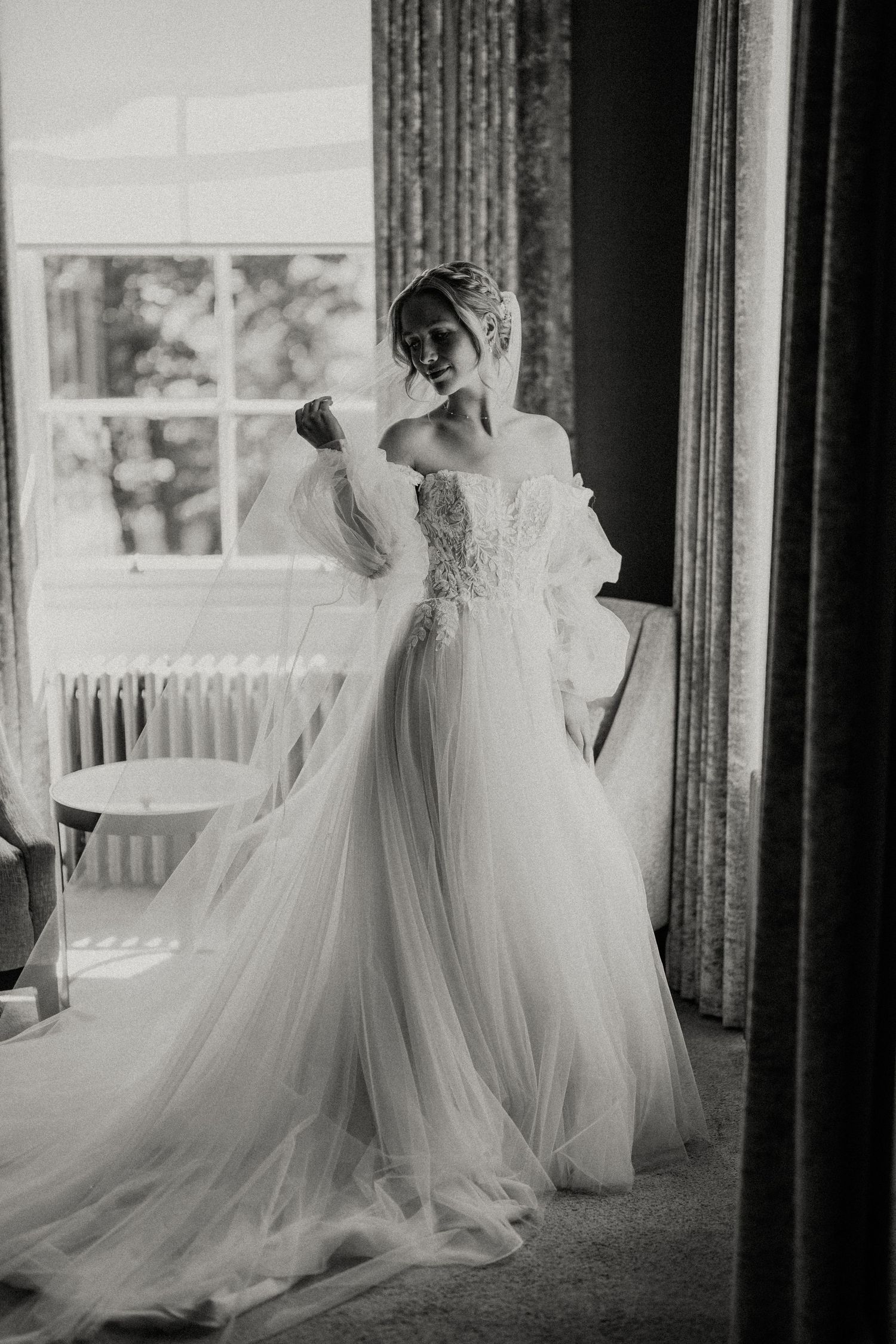 Dramatic black and white photo of wedding dress silhouette against window light.