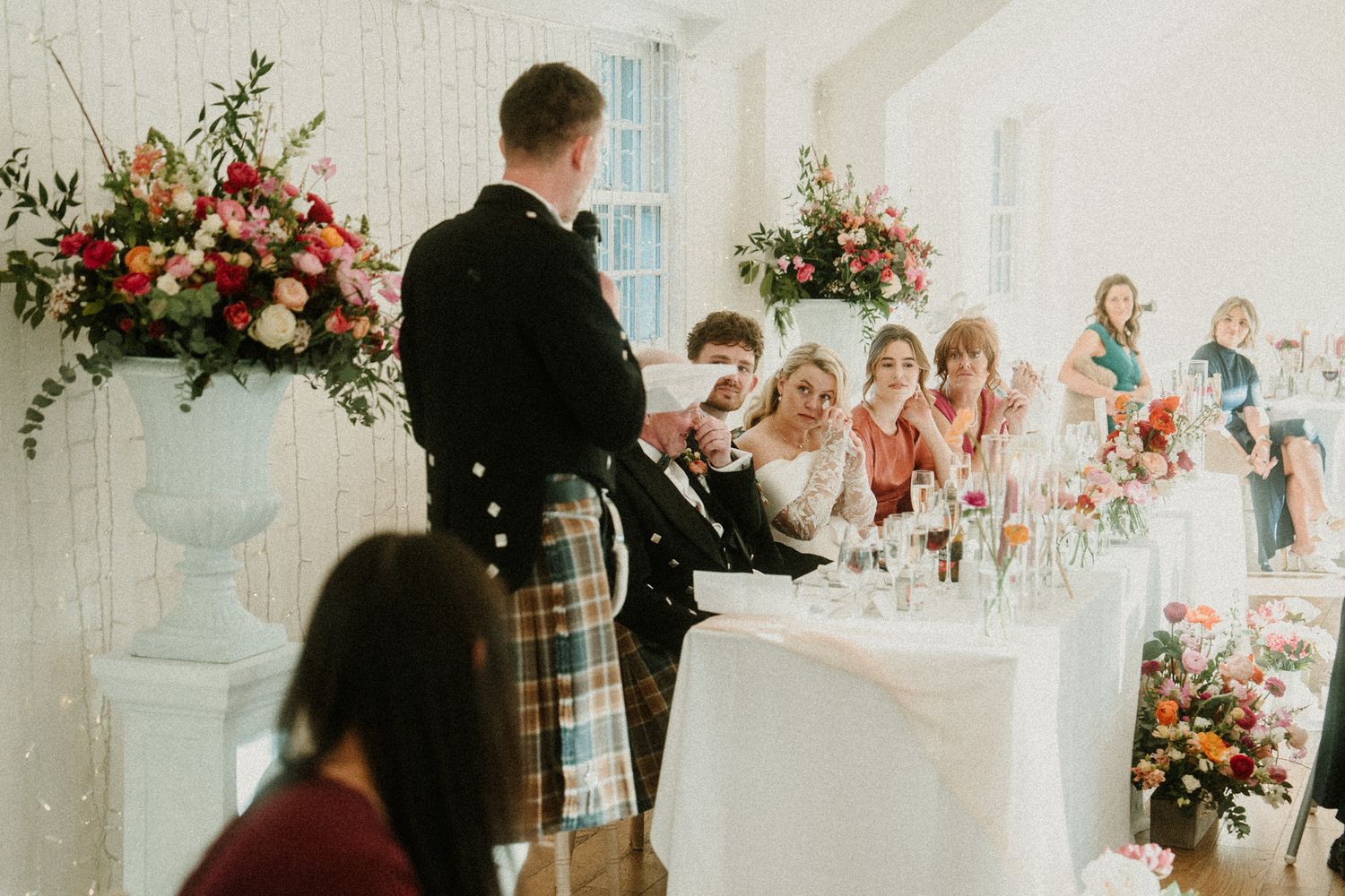 Wedding reception space decorated with pink and white flowers and elegant table settings.