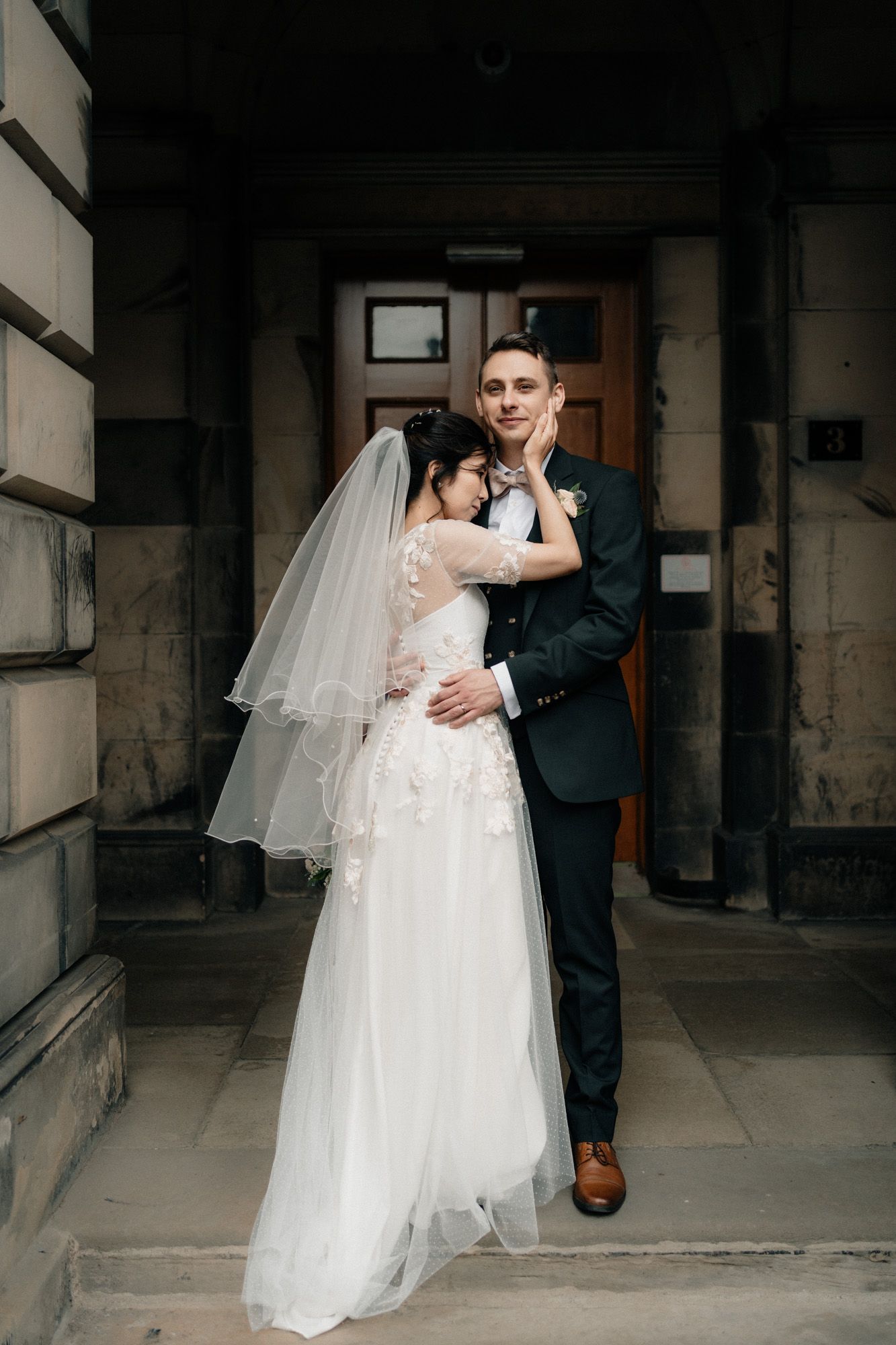 Wedding couple sharing intimate moment in dimly lit stone hallway.