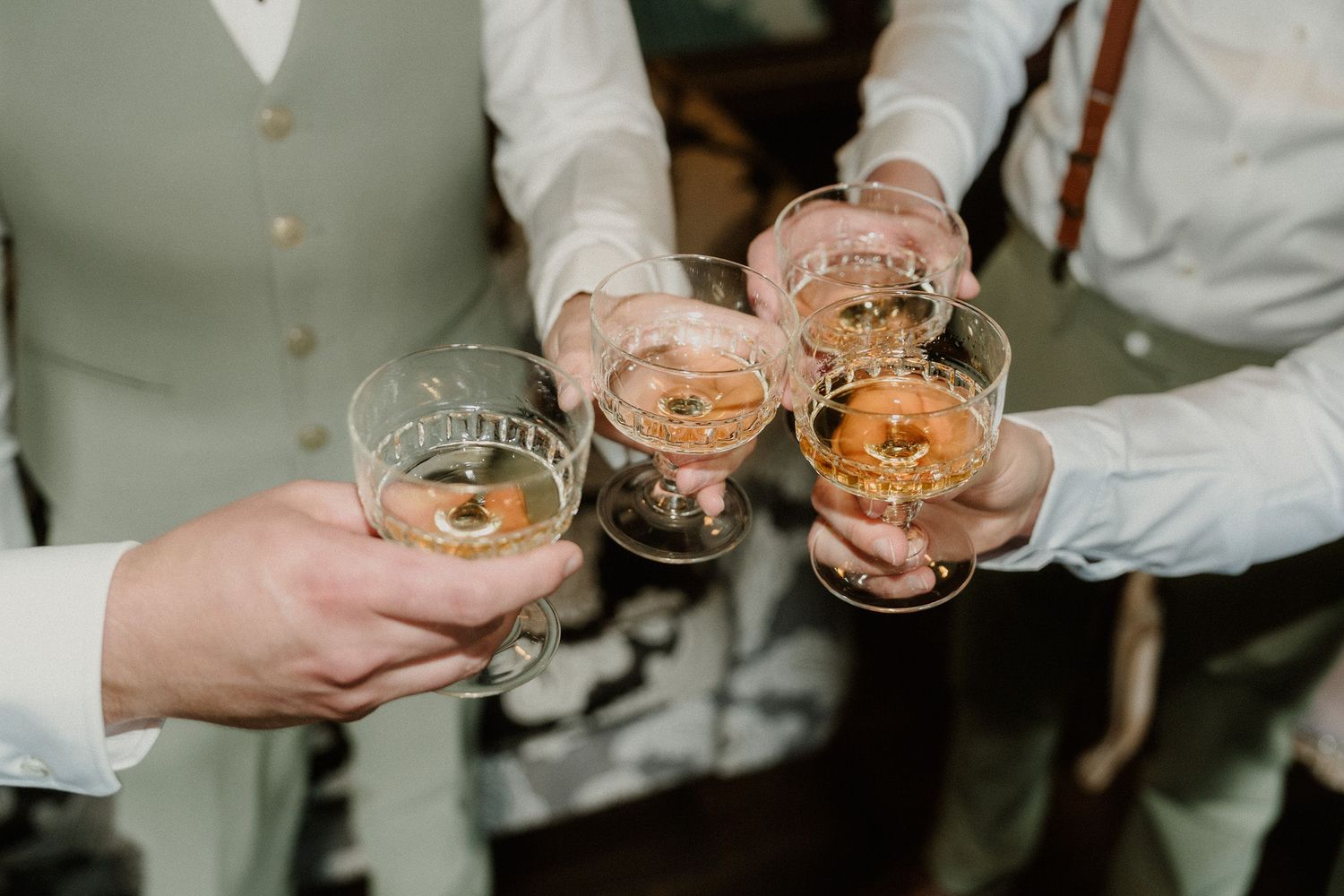 People clinking glasses of whiskey or bourbon in a celebratory toast at a formal event or wedding reception.