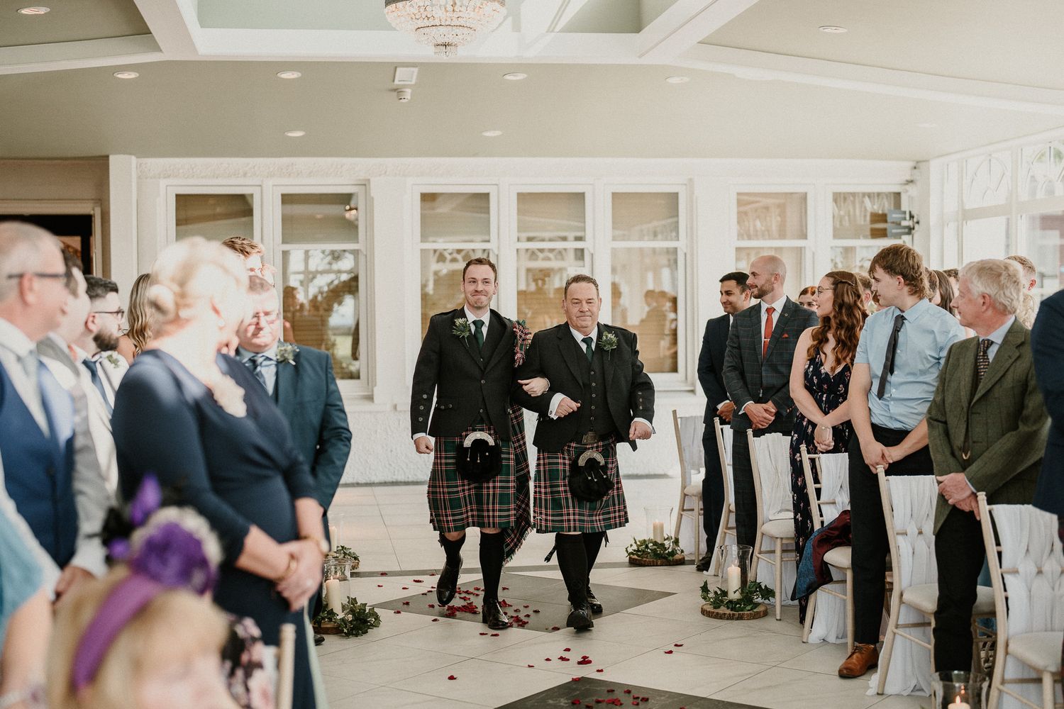 Panoramic view of wedding guests standing in an elegant white reception hall.