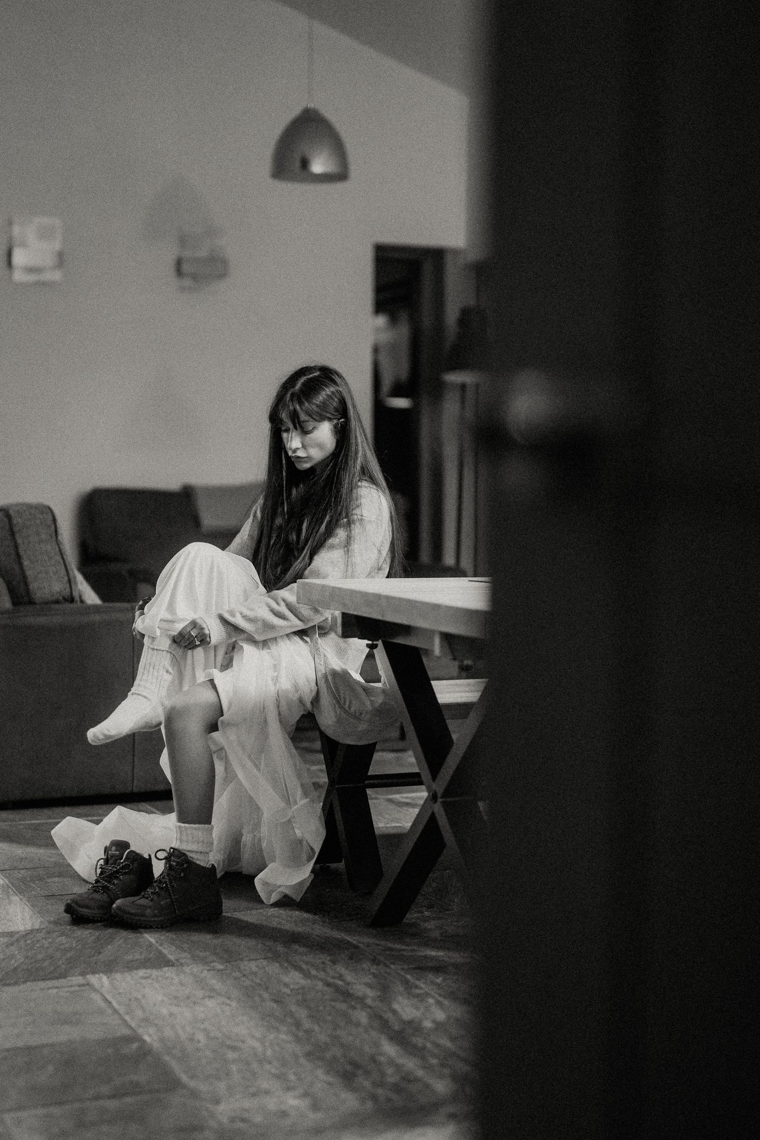 Artistic black and white indoor portrait with dramatic shadows and flowing white fabric.