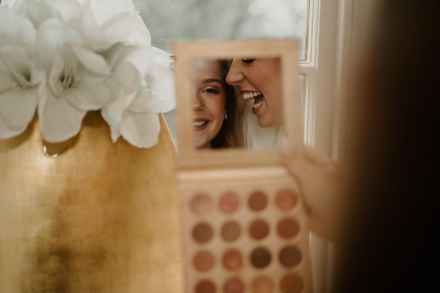 Soft focus image showing makeup preparations with white flowers in foreground.