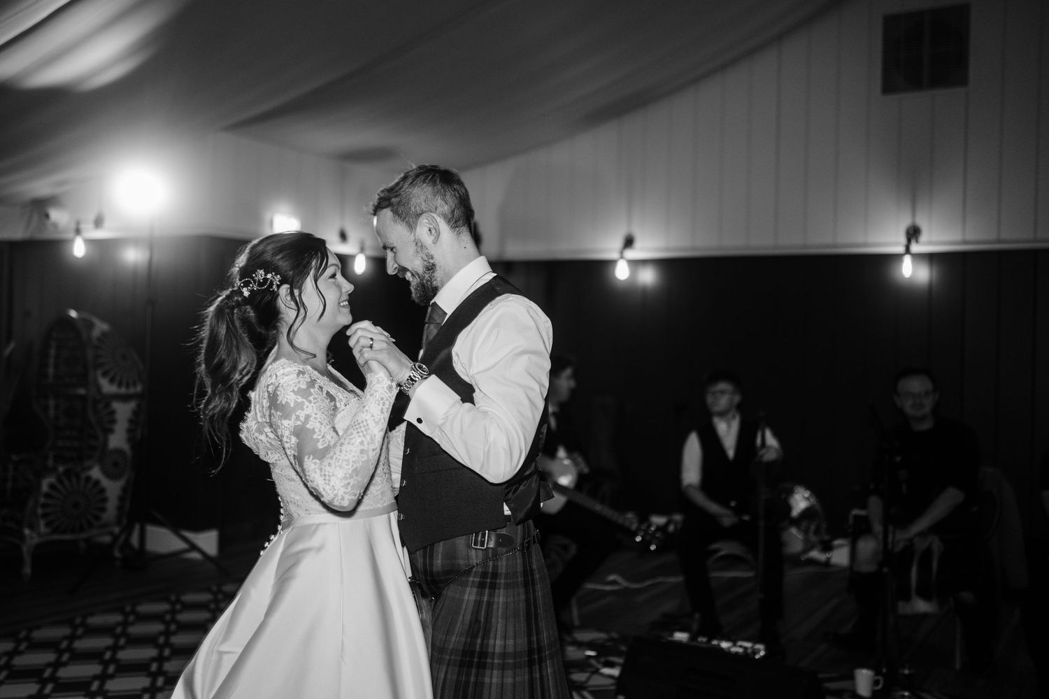 A black and white photo captures an intimate dance moment at a wedding reception.