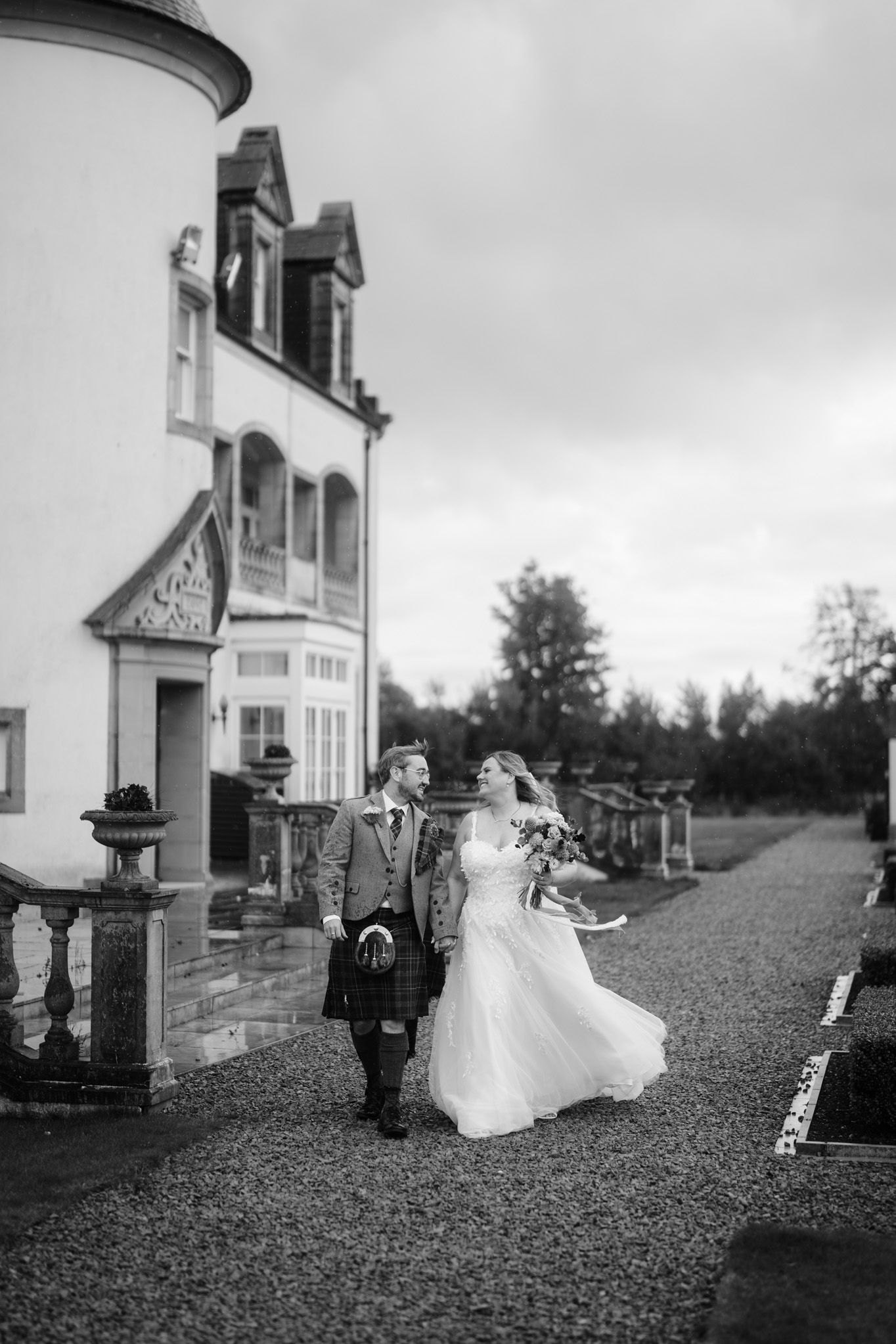 A black and white photo of newlyweds outside an elegant white building.