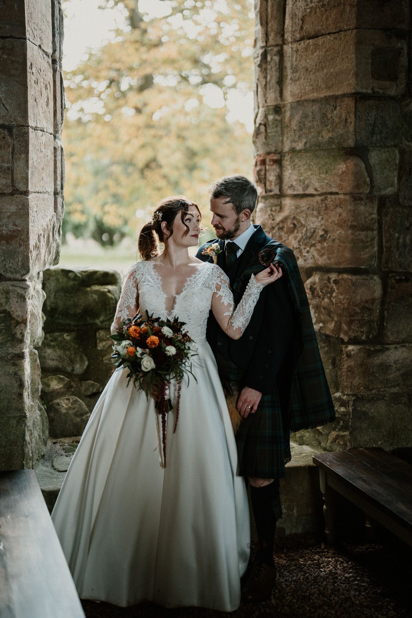 Elegant wedding photography session in stone archway with dramatic lighting.