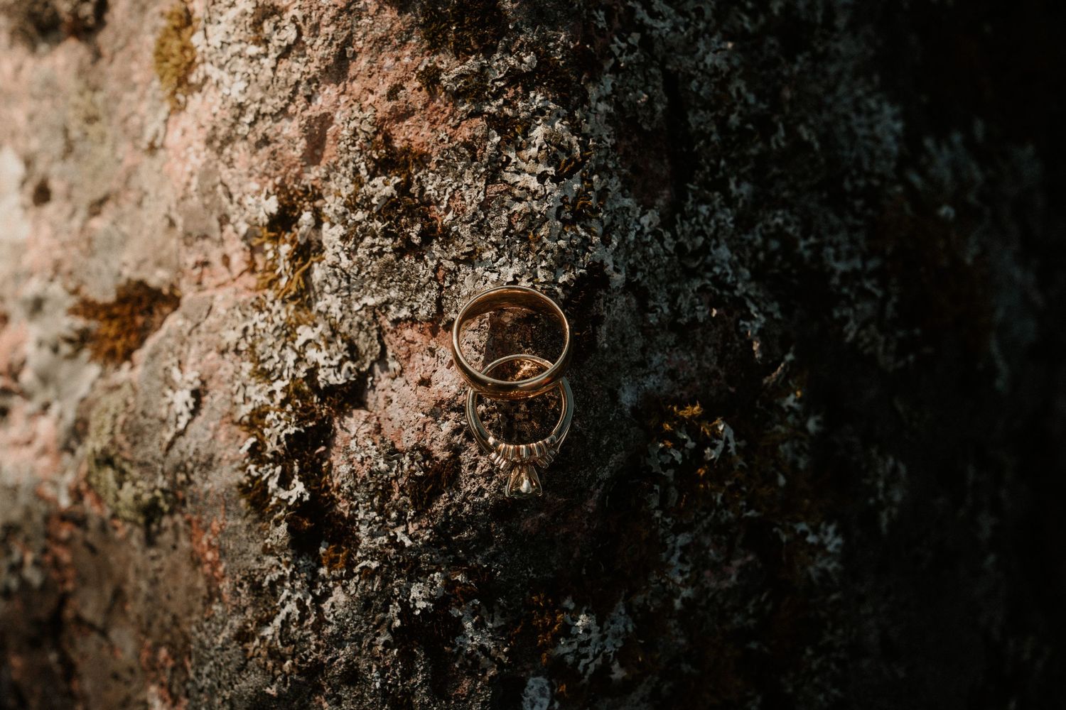 Close-up detail shots of wedding rings on textured rock surfaces.