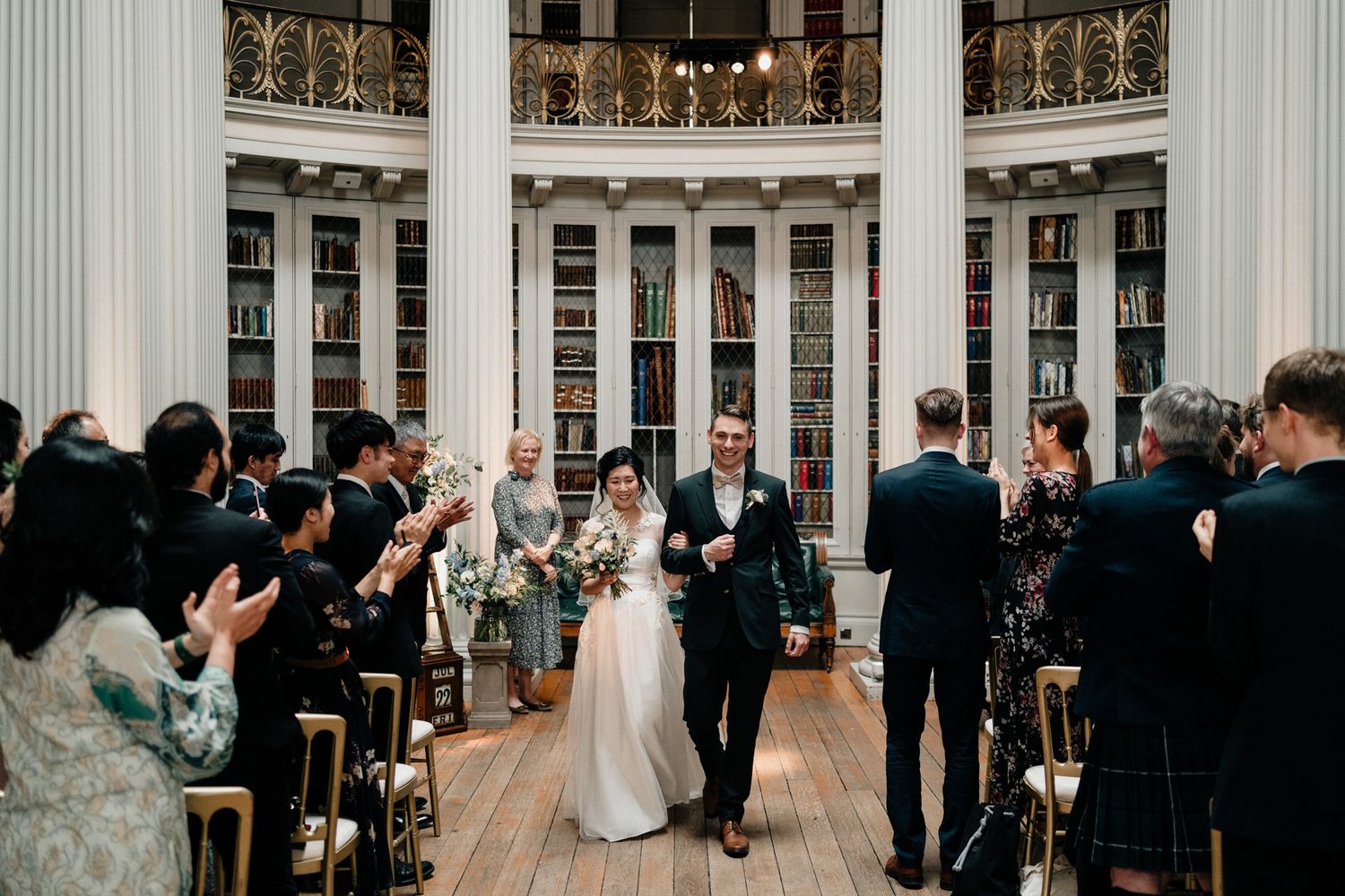 Wedding celebration in an elegant hall with guests and decorative lighting creating a festive atmosphere.