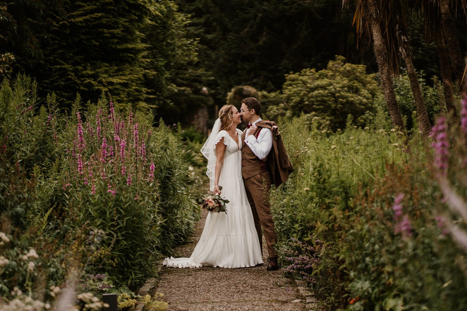 Romantic garden path portrait with wildflowers and lush greenery.