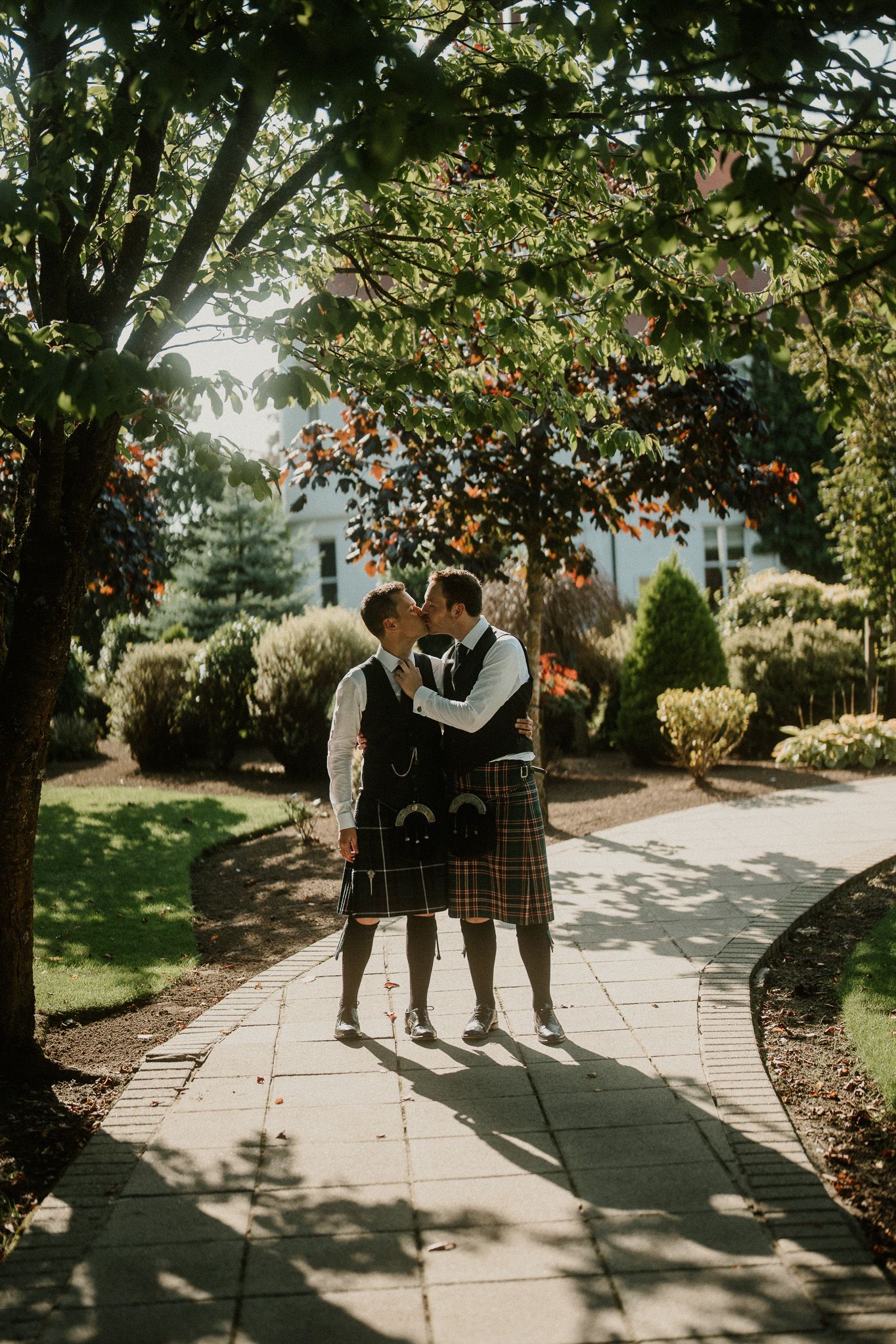 A romantic moment between two people in Scottish dress beneath autumn trees.