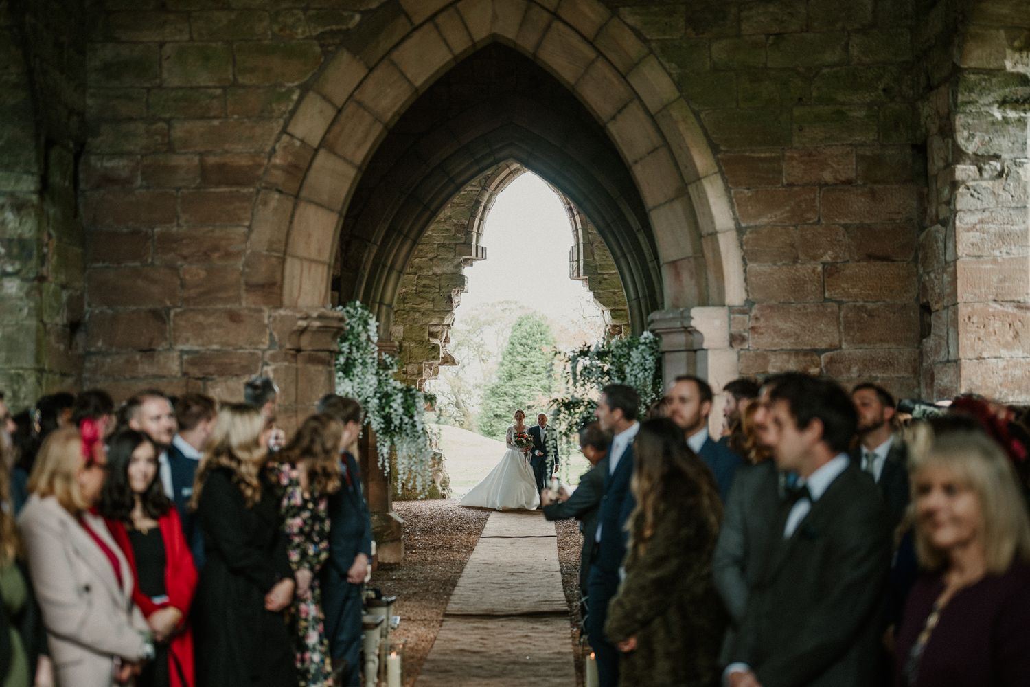 Stone archways and natural light create dramatic atmosphere for indoor wedding ceremony.