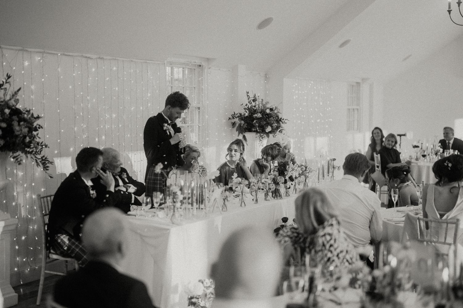 Wedding reception hall with white decor and elegant table settings.