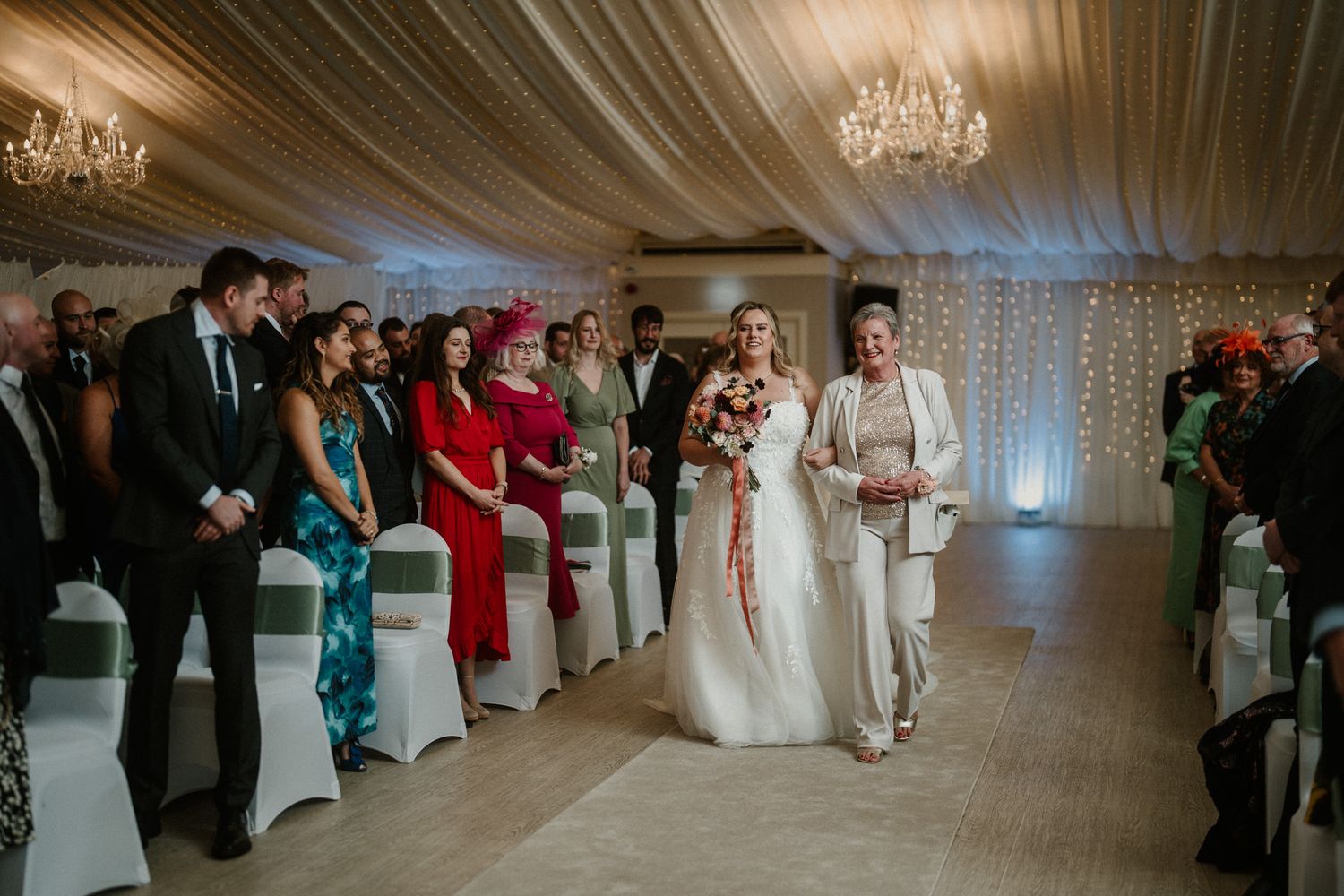 Elegant wedding reception space with crystal chandeliers and white fabric draped ceiling.