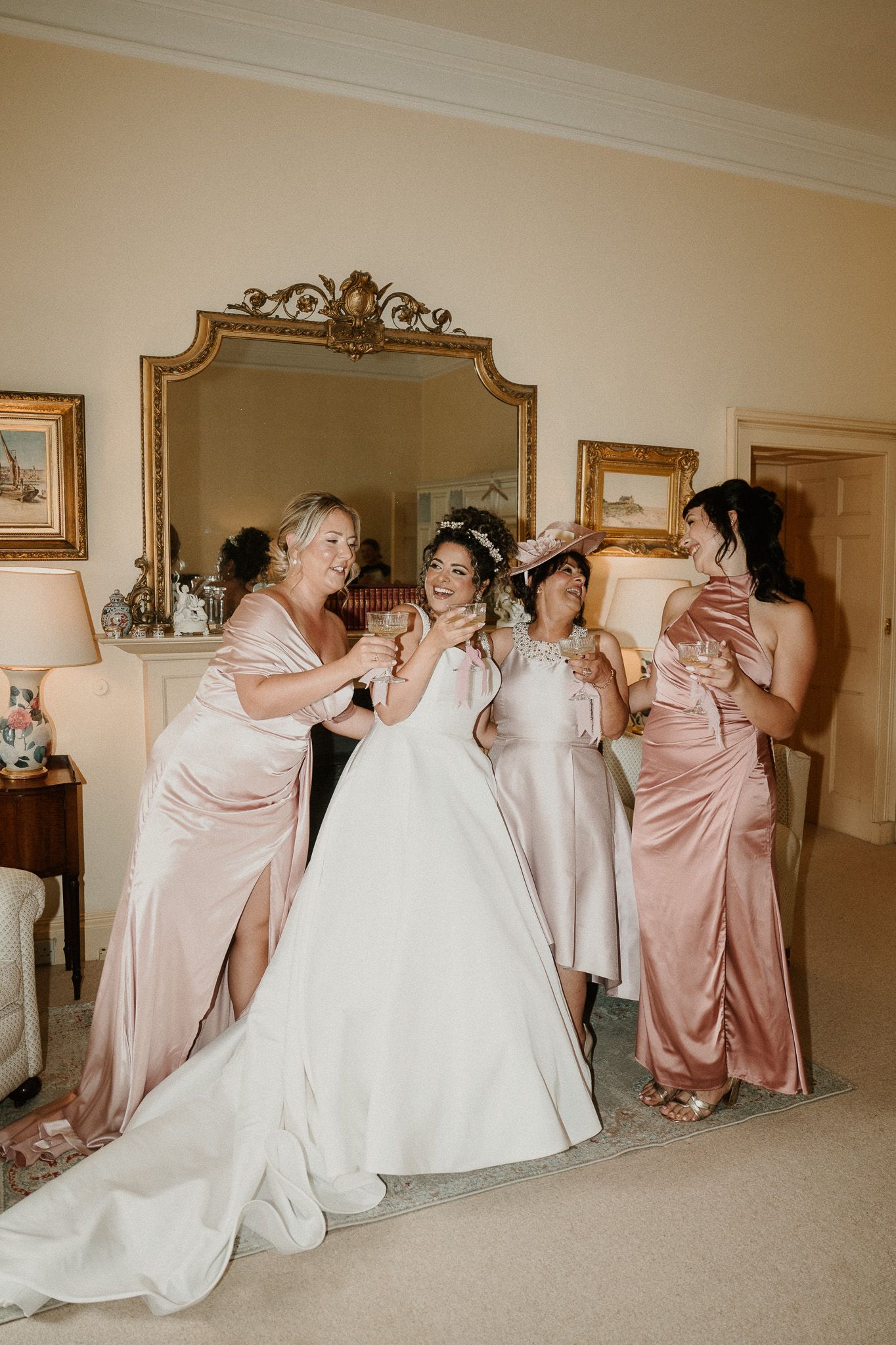Wedding party members in pink dresses create a domino effect pose with the bride in white.