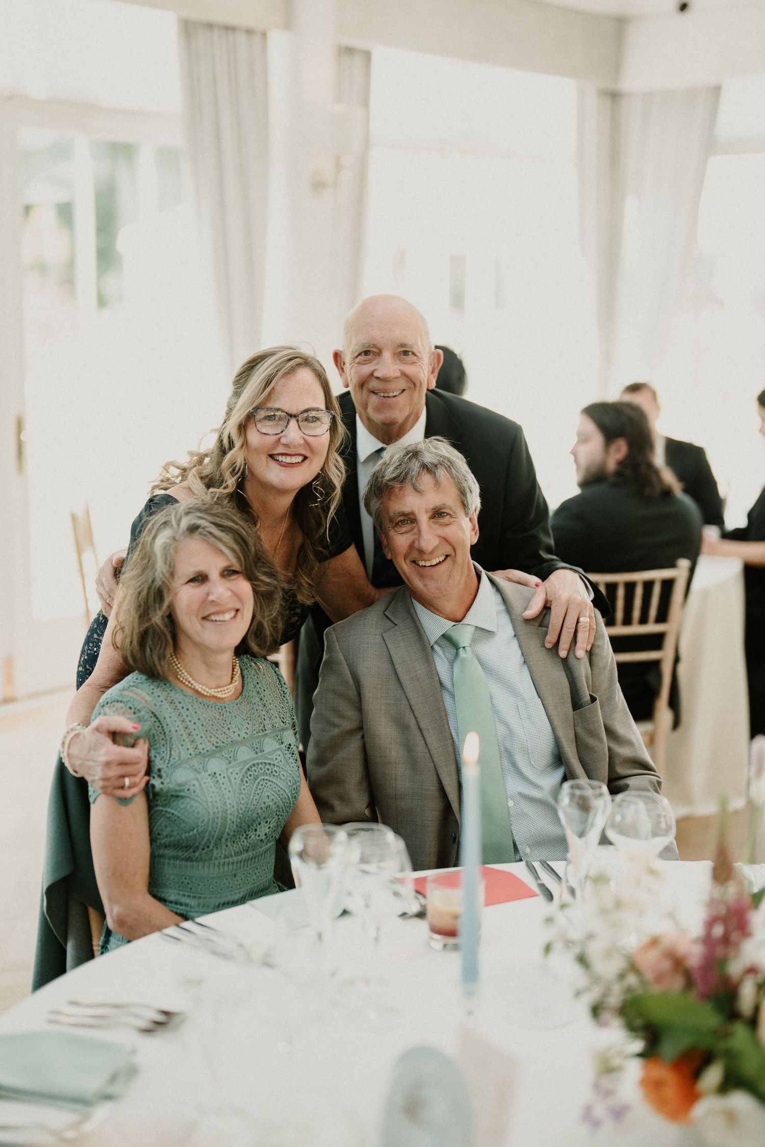 Wedding guests enjoying themselves at an elegant indoor reception with white tablecloths.