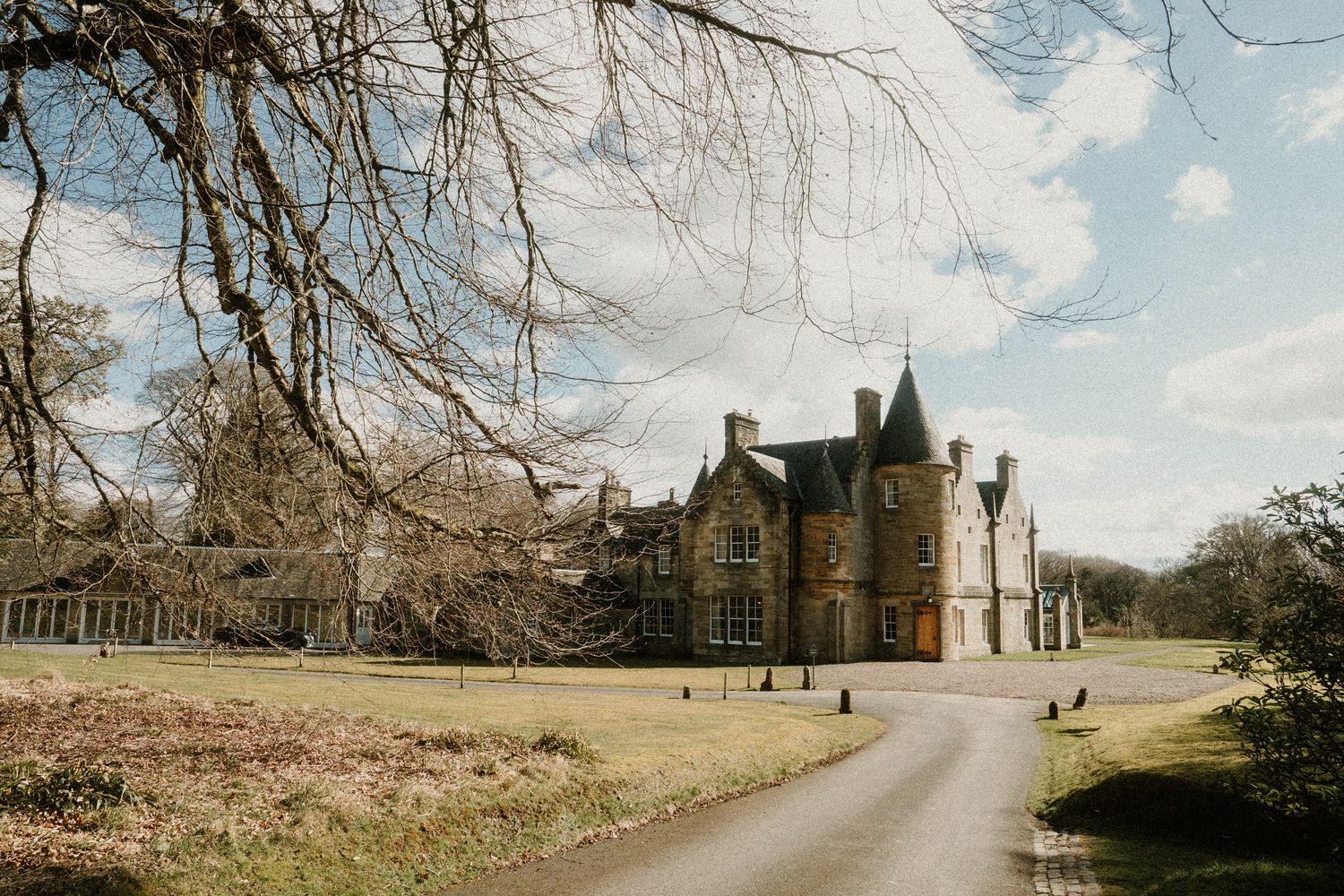 Panoramic view of a Scottish castle and grounds under cloudy skies.