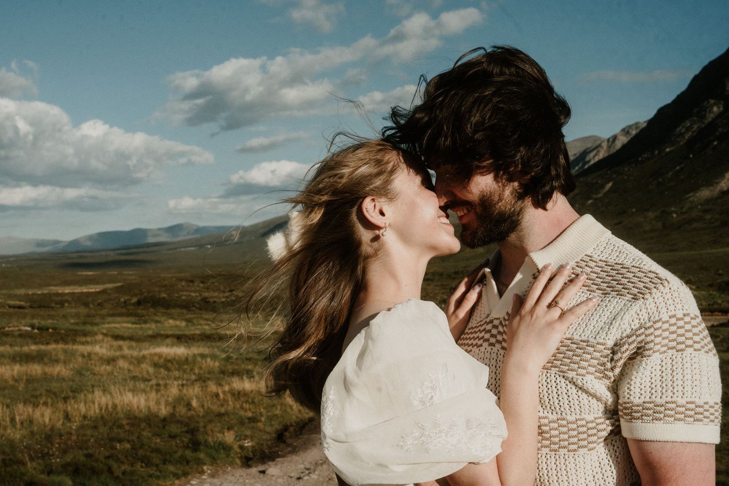 Intimate moment captured in Scottish highlands with dramatic mountain backdrop.