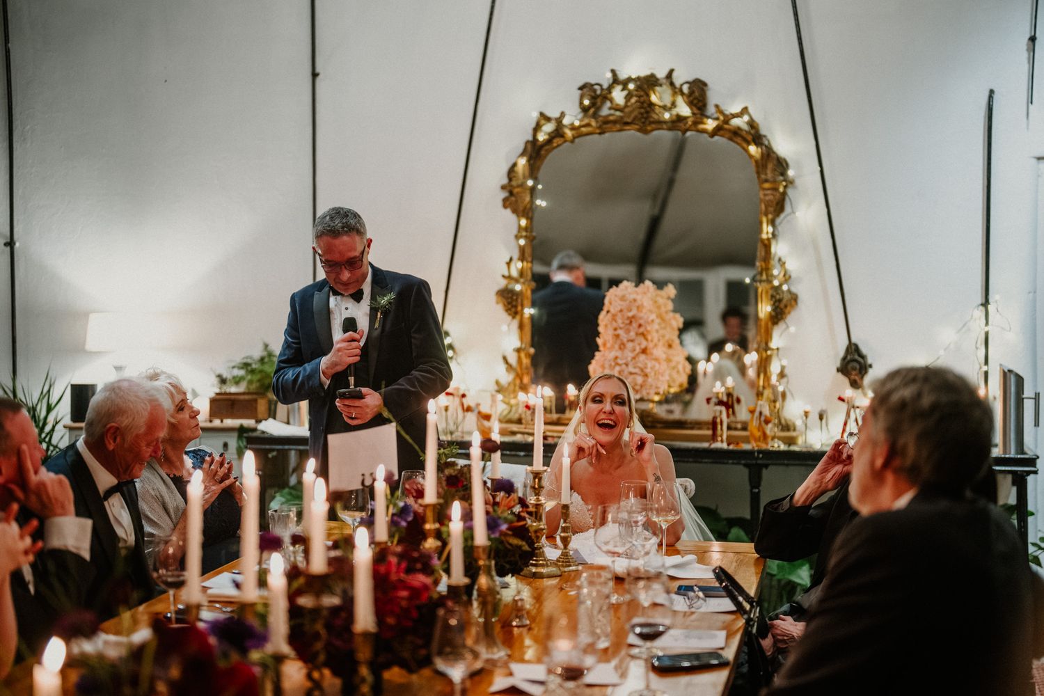 Wedding reception venue features vintage gold mirrors and warm ambient lighting creating an intimate atmosphere.