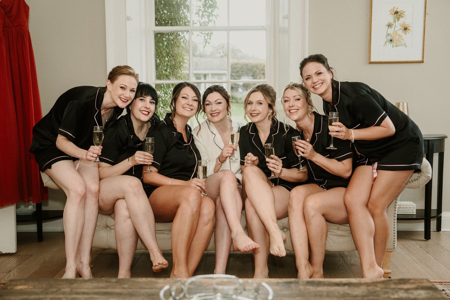 People in matching black and white outfits sit together on a couch in a bright room.