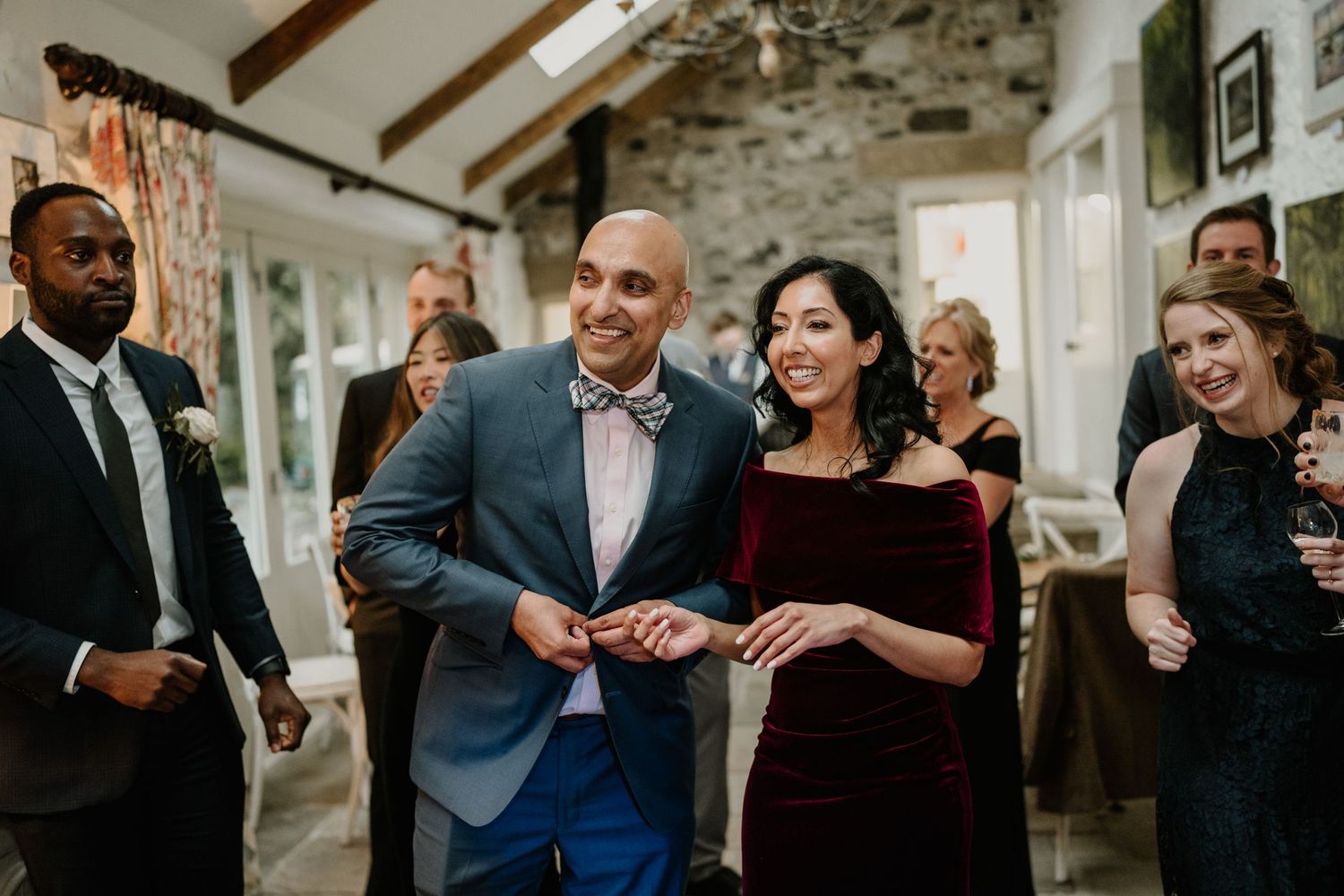 Wedding guests dancing and celebrating in an elegant stone-walled venue.