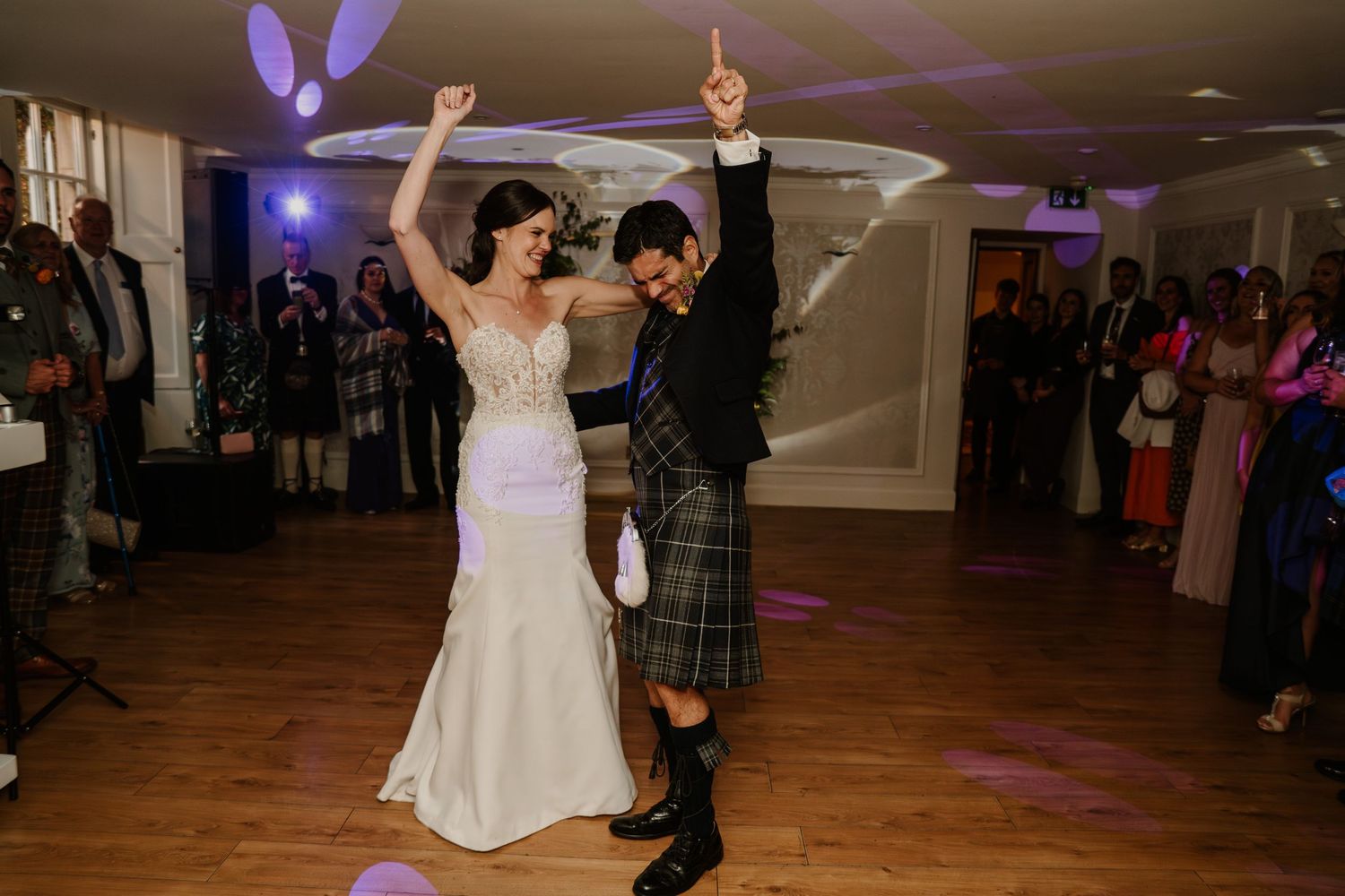 Wedding reception dance floor with purple ambient lighting and wooden flooring.