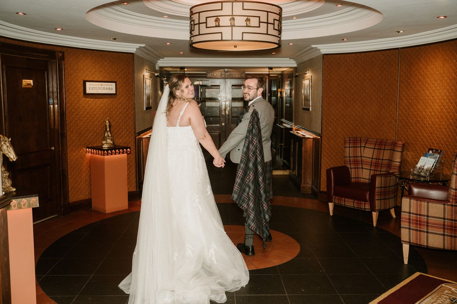 A panoramic view of an elegant hotel hallway with warm lighting and geometric ceiling details.