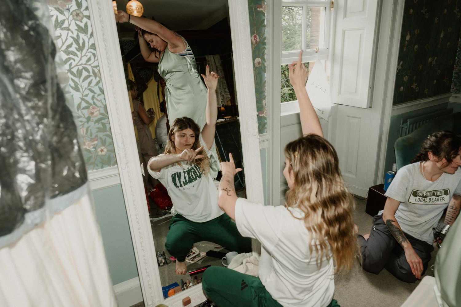 Group of young women celebrating together in a room, raising hands joyfully during a fun indoor gathering.