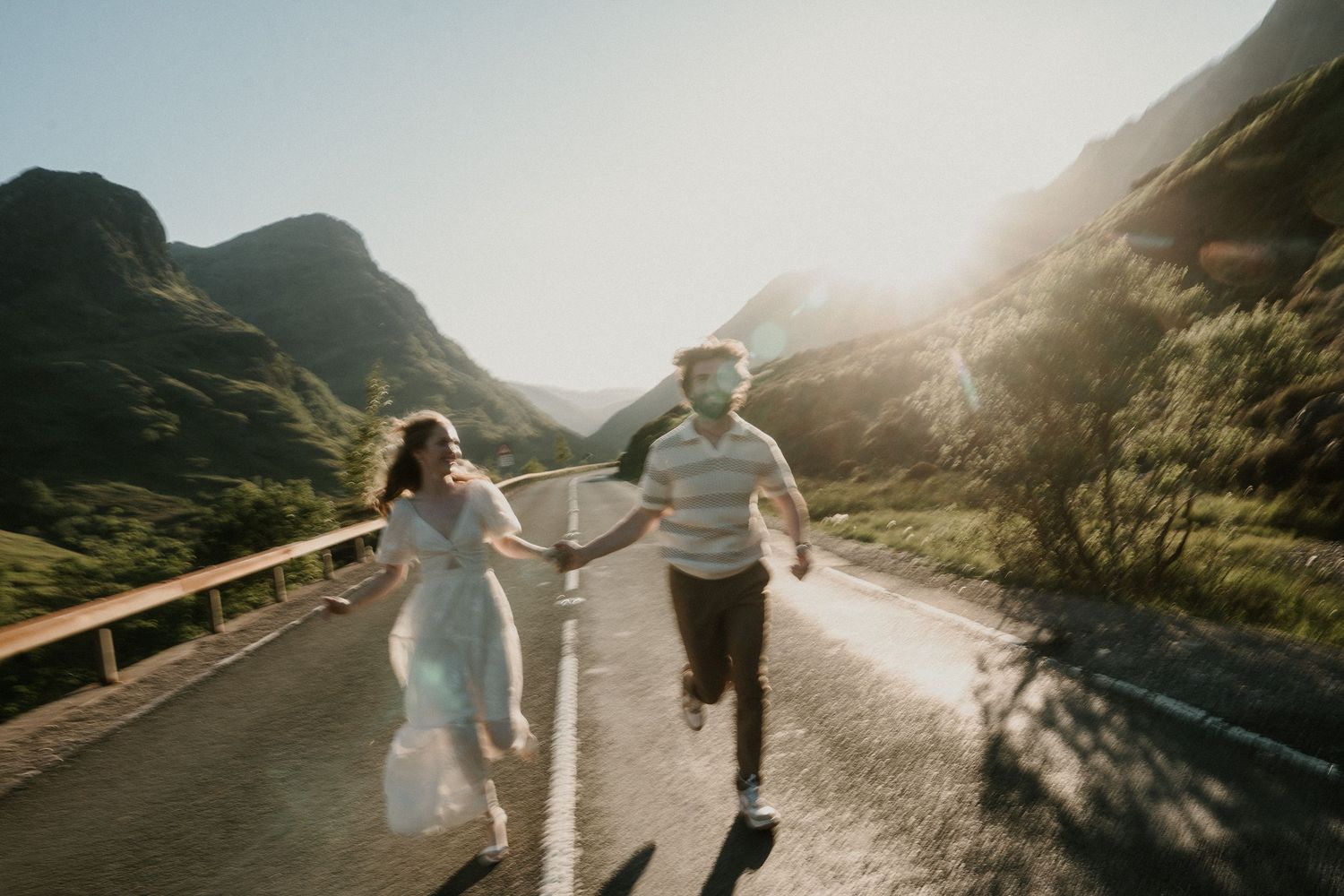 Couple walking hand in hand on mountain path during golden hour.