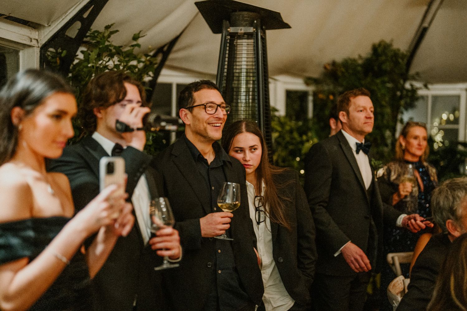 Wedding guests mingle during golden hour at an outdoor cocktail reception.