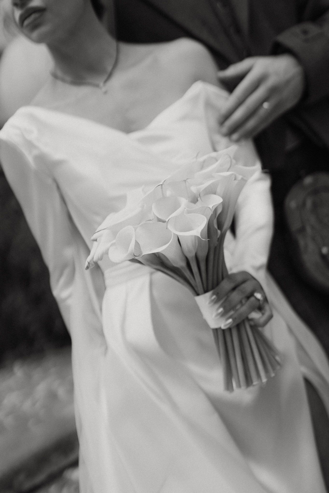 Black and white series of wedding photos showing close-up details of a bride's white dress and floral bouquet.