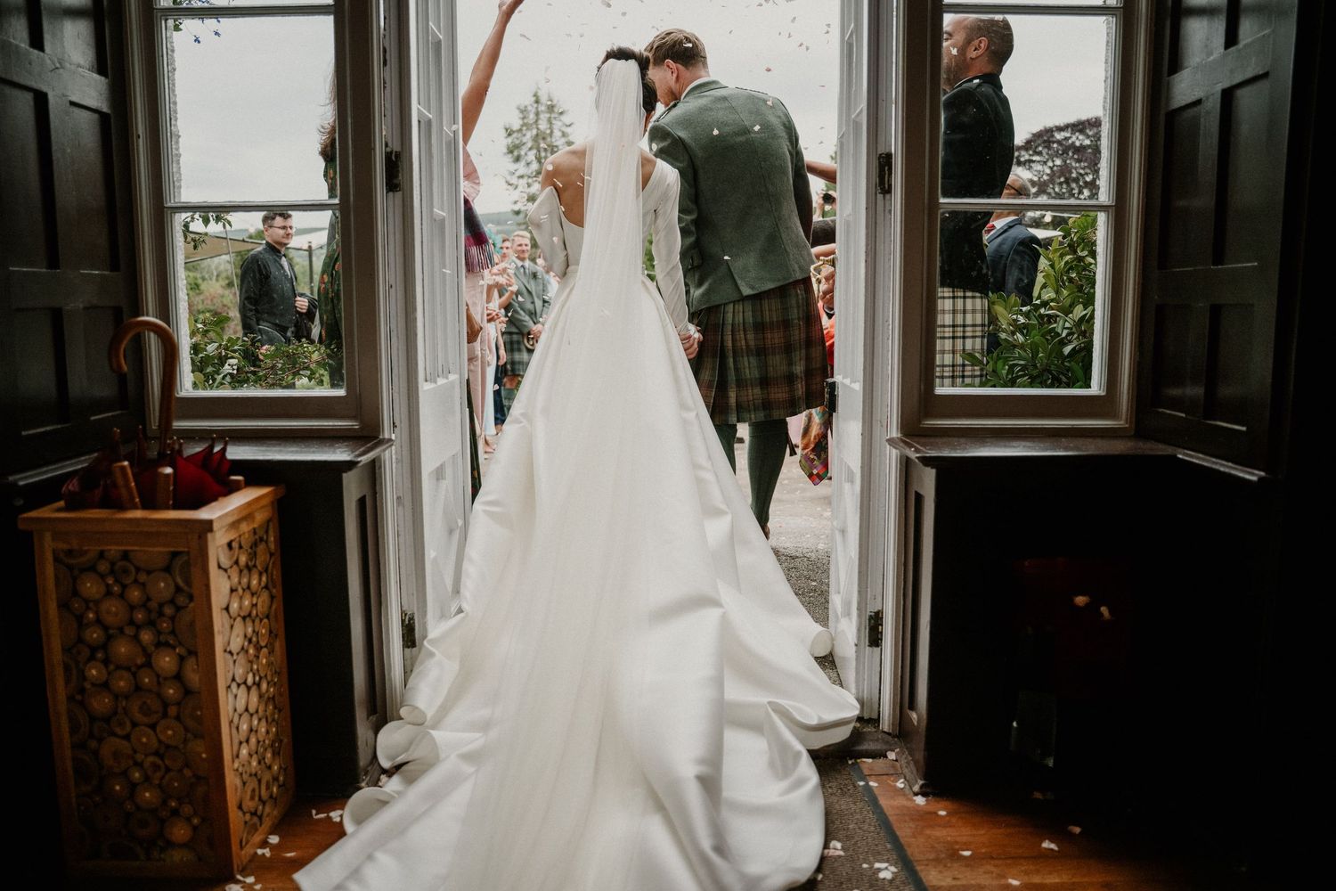 A couple shares an intimate moment in a beautiful historic room with ornate decor and natural light streaming through windows.