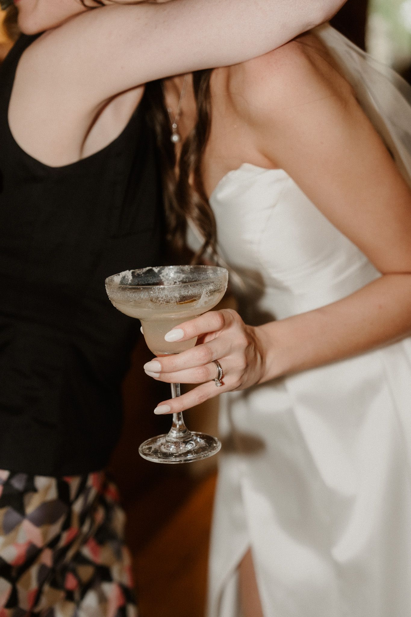 Bride in white strapless gown holding a margarita glass with salted rim at a wedding reception.