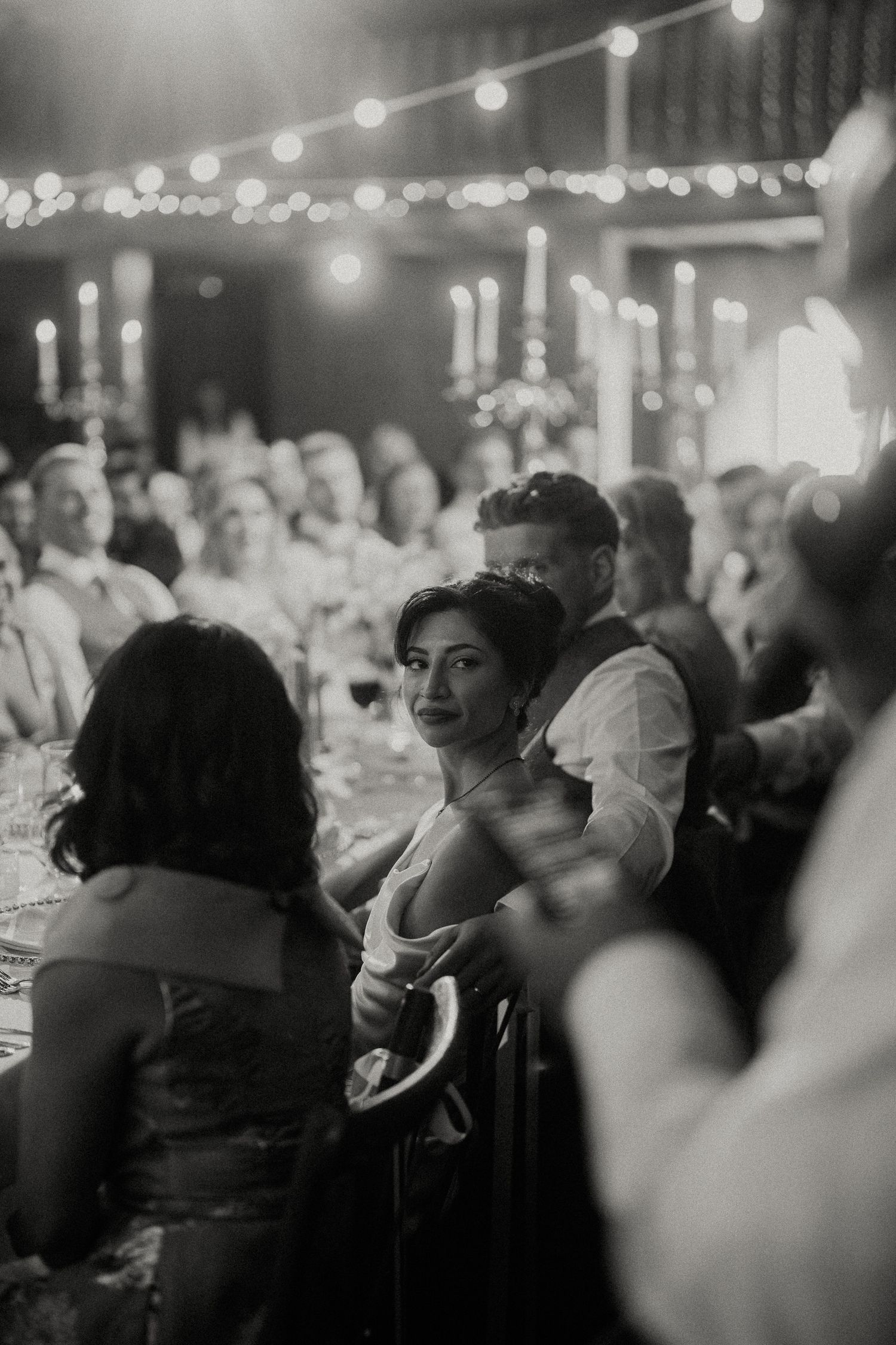 Wedding guests enjoying the reception under warm string lights and candlelight.