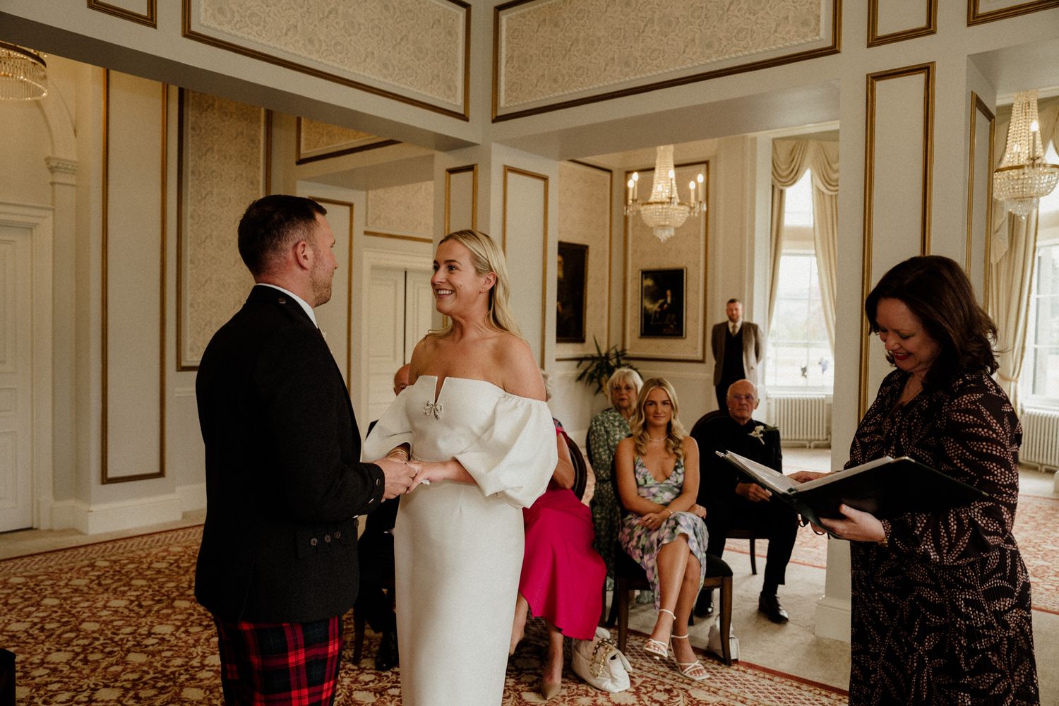Wedding ceremony candid moments in a luxurious ballroom with classic architectural details.