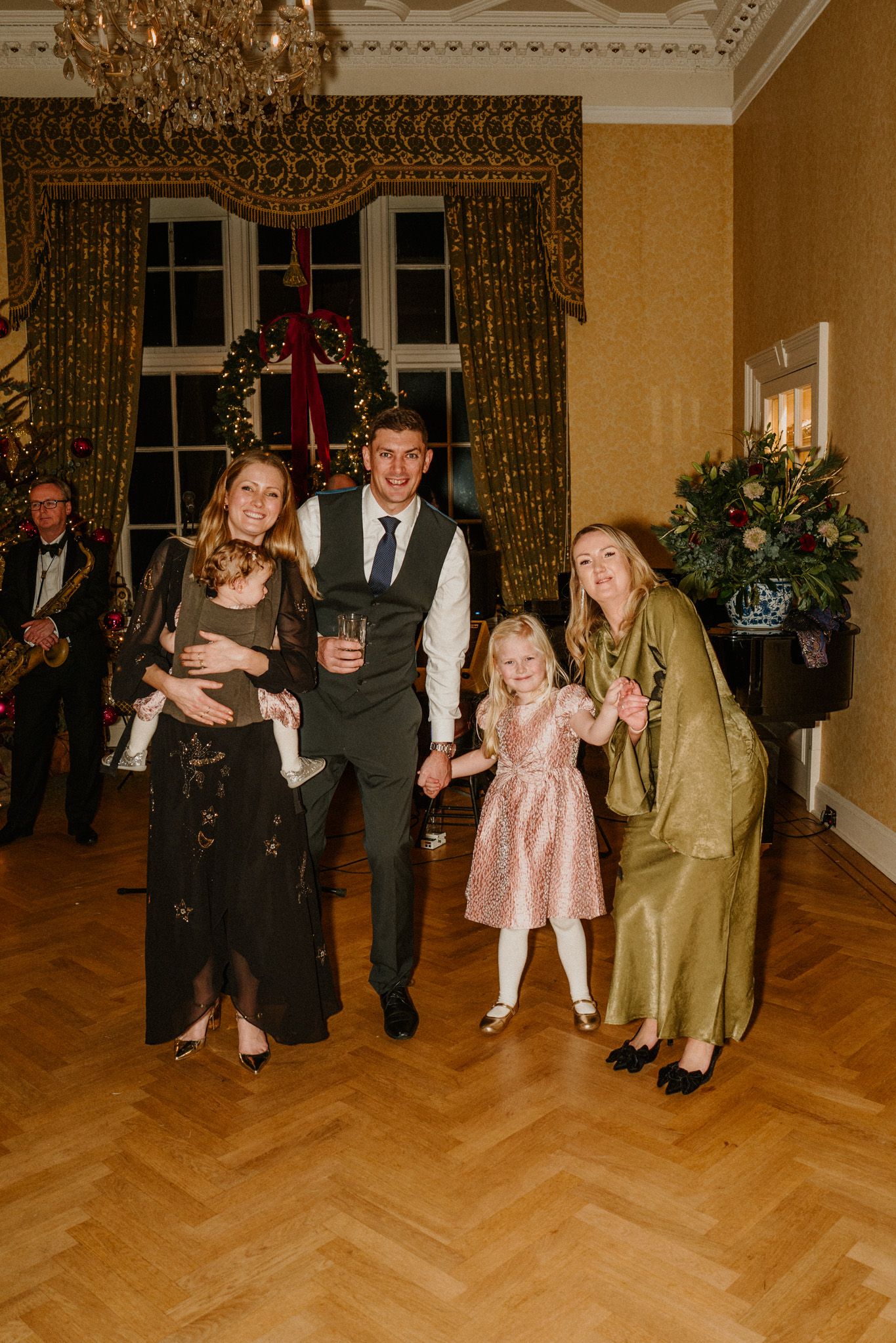 Wedding guests in formal attire dance and socialize in an elegant ballroom setting.