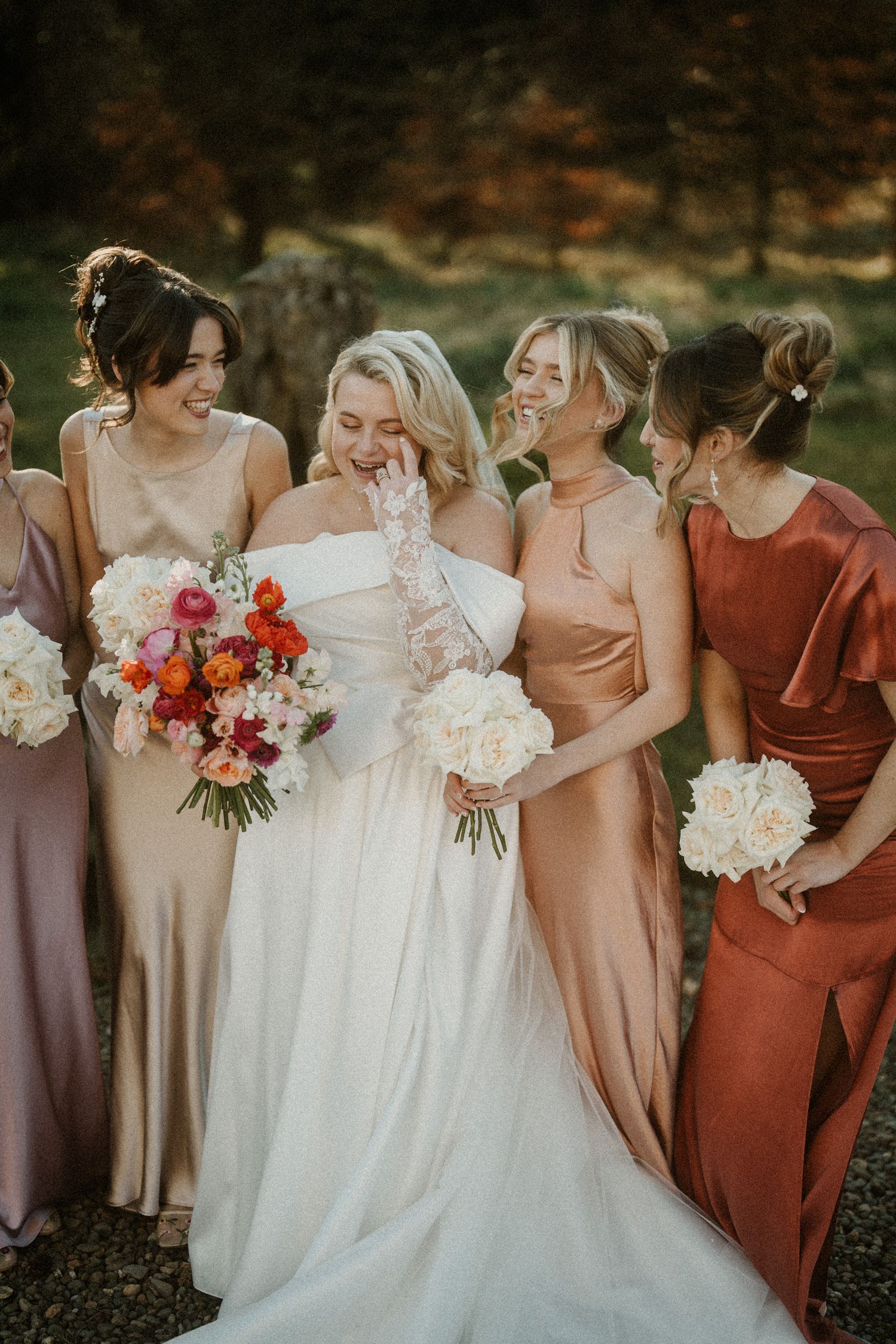 Close-up of bridal party showing details of dresses and floral bouquets in autumn colors.