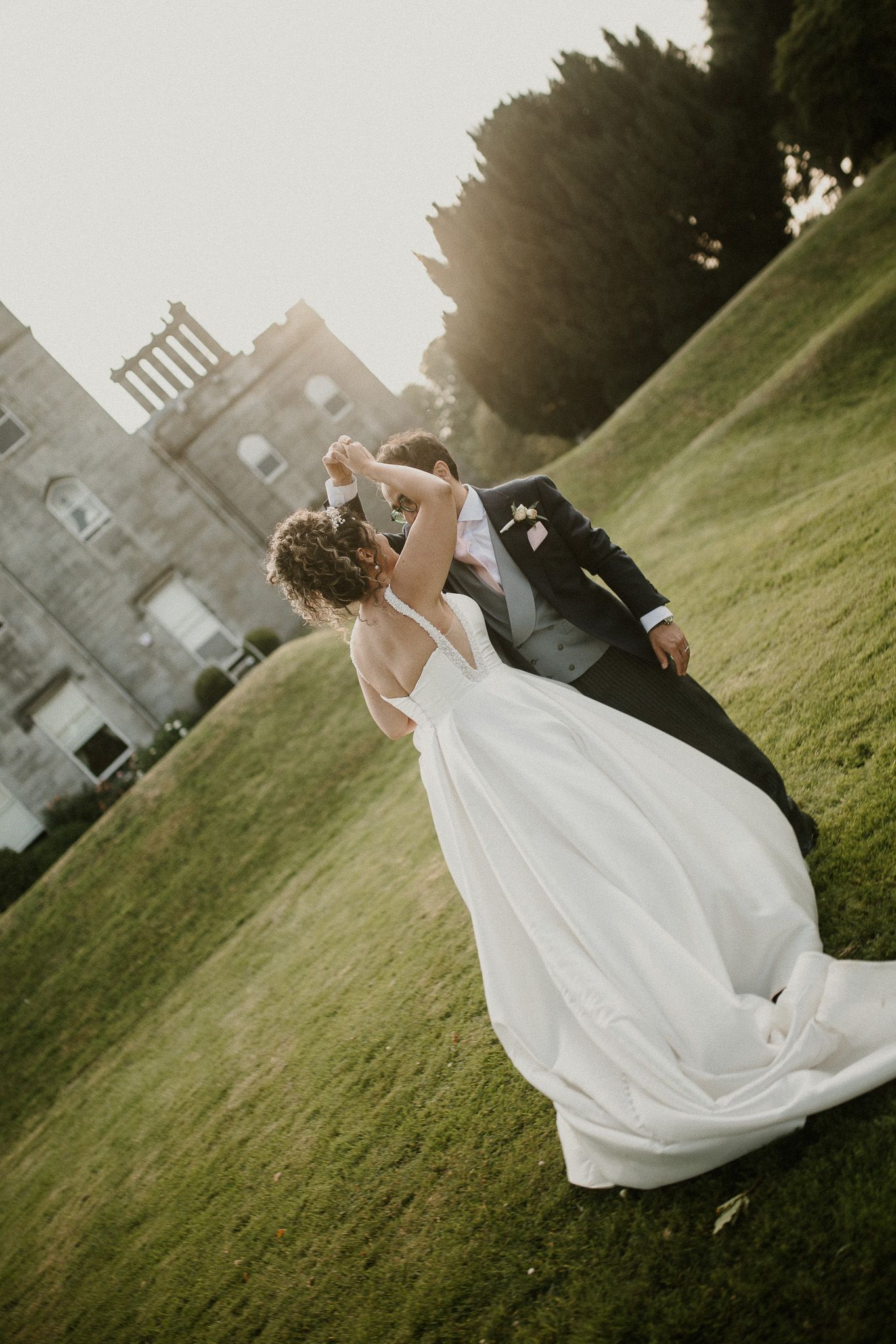Romantic sunset dance on castle grounds with flowing white wedding gown.