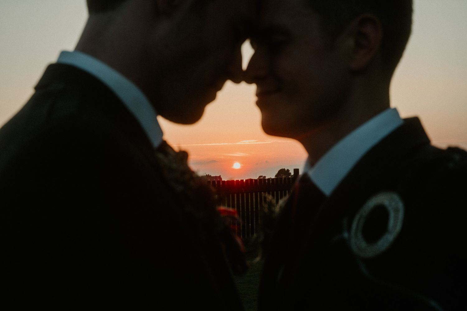 Silhouetted couple shares an intimate moment against a dramatic sunset backdrop.