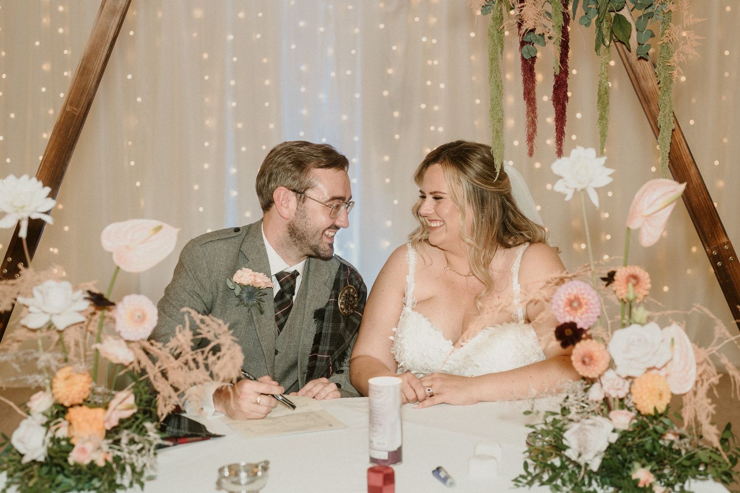 Wedding reception table decorated with soft pink florals and romantic lighting.