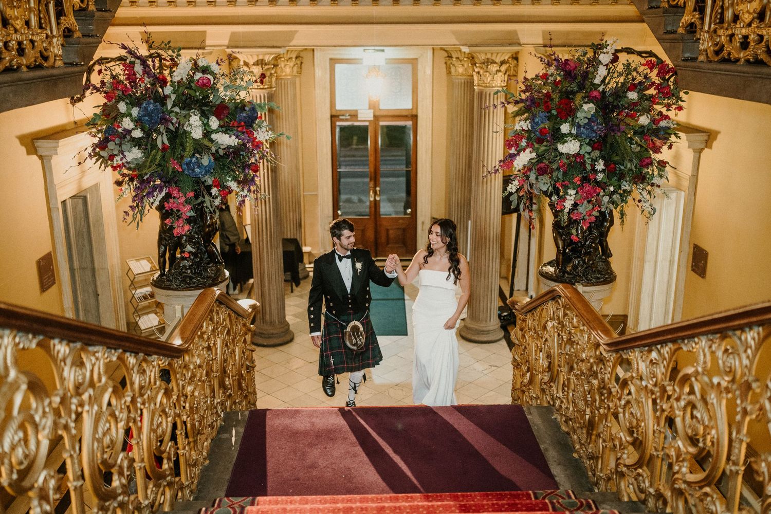 A grand staircase decorated with floral arrangements and golden accents in an opulent venue.