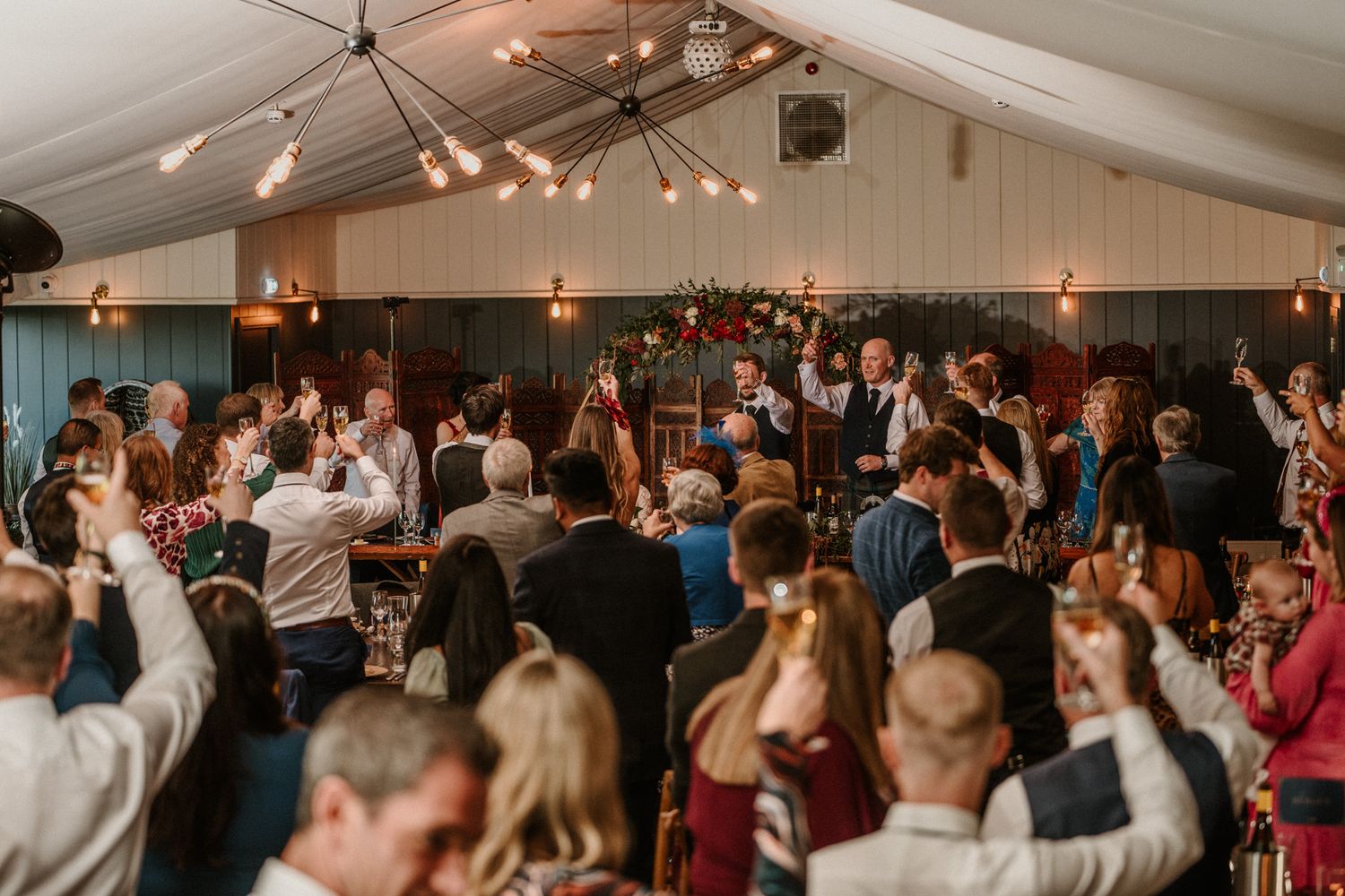 Guests enjoying a wedding reception celebration with string lights overhead.