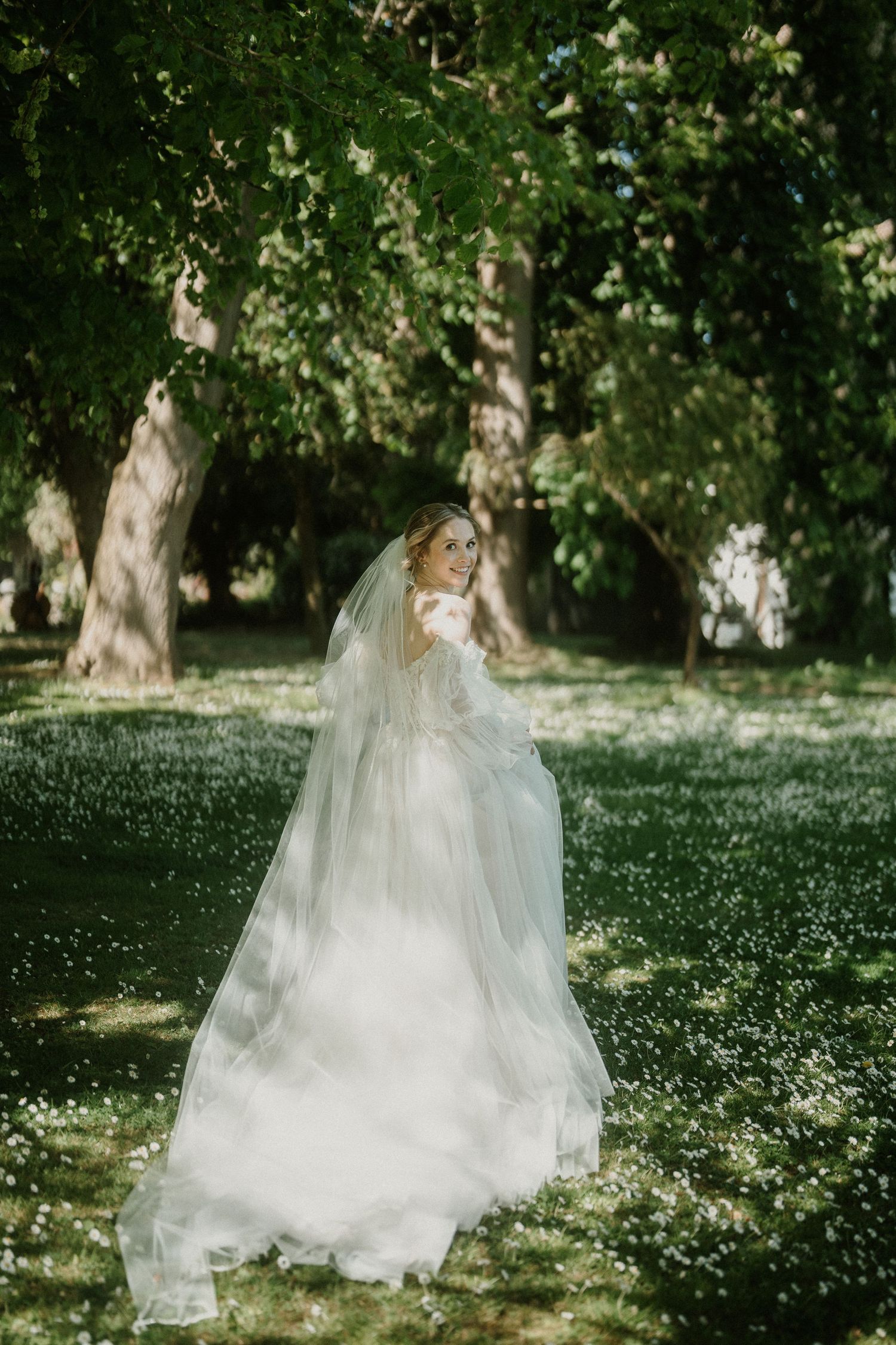 Ethereal bridal portrait in a meadow with flowing white dress and scattered wildflowers.