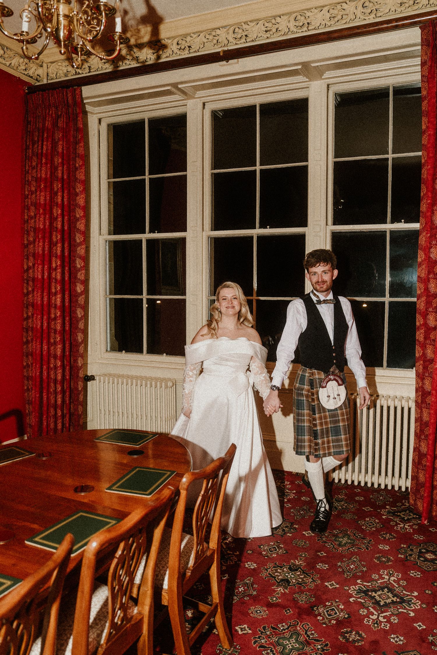 Elegant room with red curtains and ornate molding featuring wedding celebration moments.